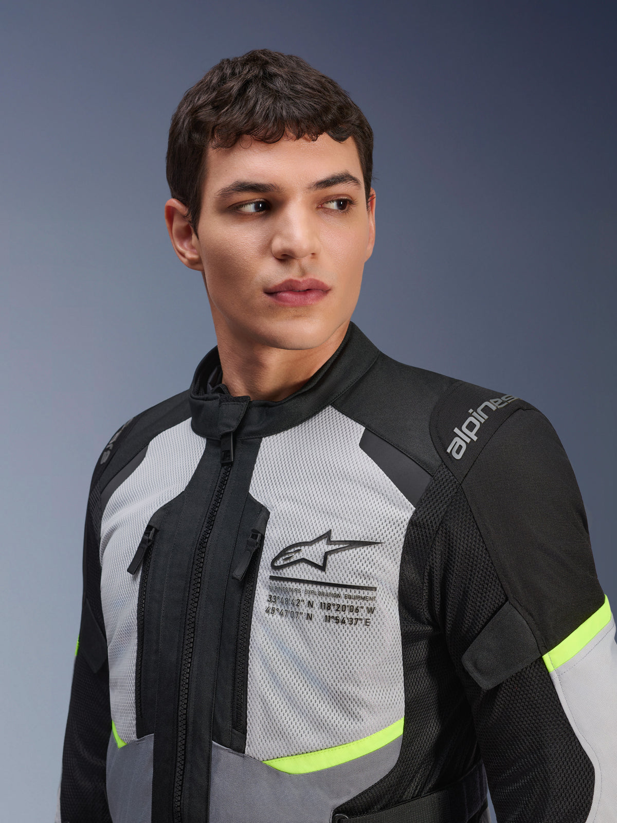 Alpinestars Andes Air Drystar® Jacket, Motorcycle Touring Jacket, Ice Grey and Dark Grey with Neon Yellow accents, worn by a male model, featuring 2D mesh panels for ventilation, Alpinestars logo with coordinates on the chest, and durable textile construction.