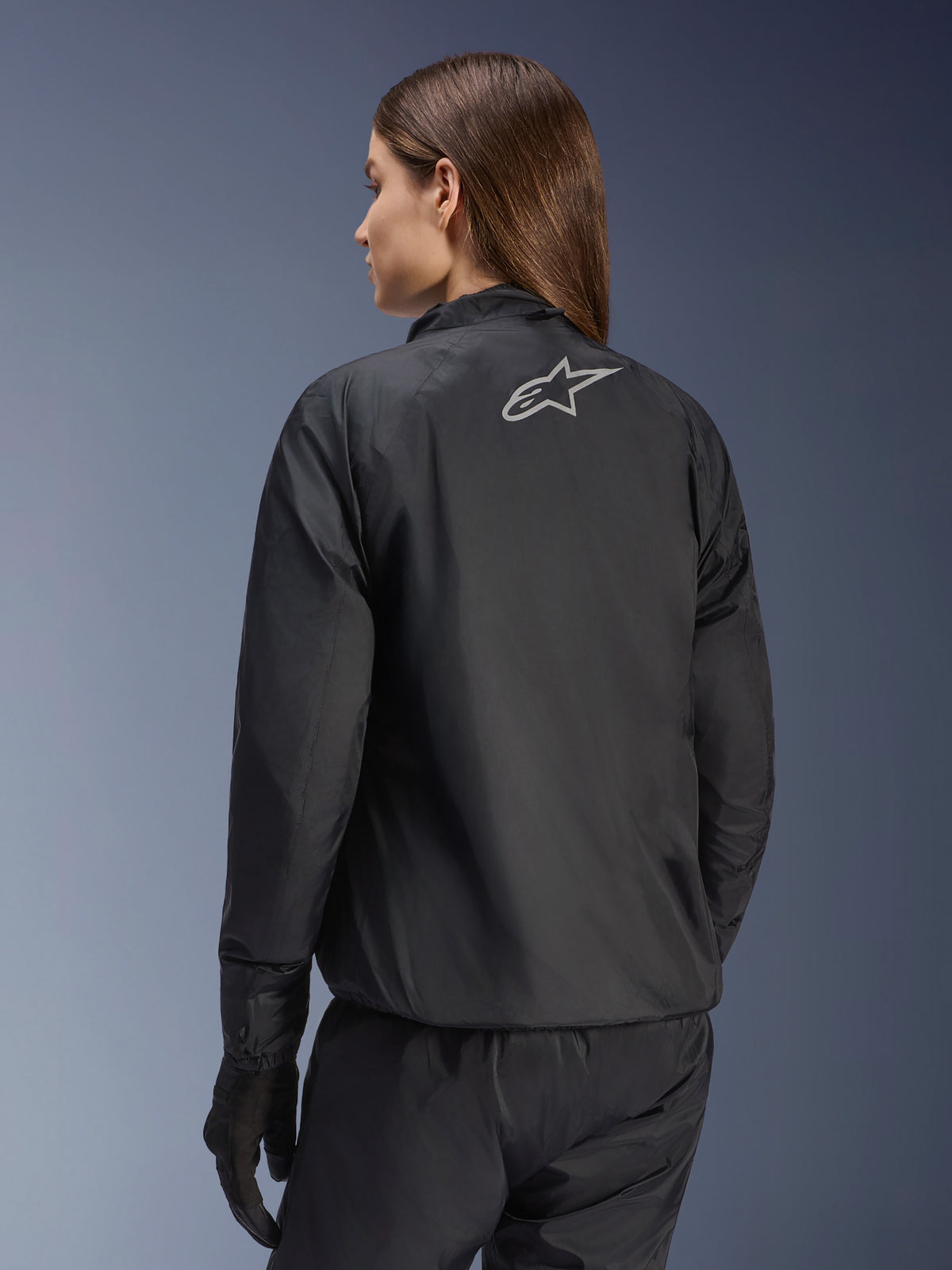 Kurtka Alpinestars Stella Andes Air Drystar®, damska kurtka motocyklowa, czarna, widok z tyłu pokazujący srebrne logo gwiazdy, zestawiona z czarnymi spodniami i rękawicami, lekka wodoodporna odzież turystyczna