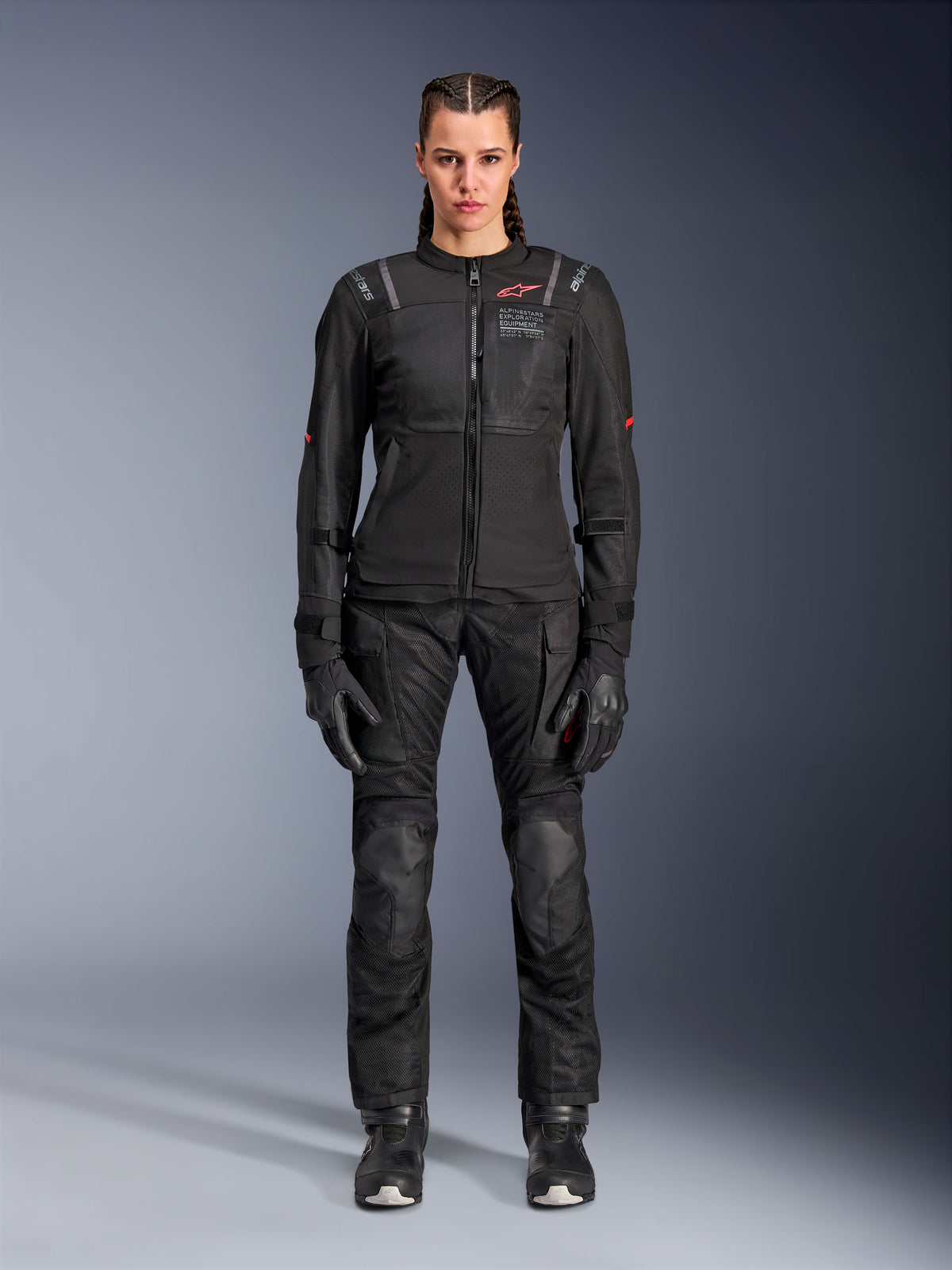 Alpinestars Stella ST-2 Air Jacket, czarna, widok studyjny całej sylwetki motocyklistki w dopasowanych czarnych spodniach motocyklowych i rękawicach, panele z siatki o wysokim przepływie powietrza, czerwone detale logo, nowoczesny design turystyczny