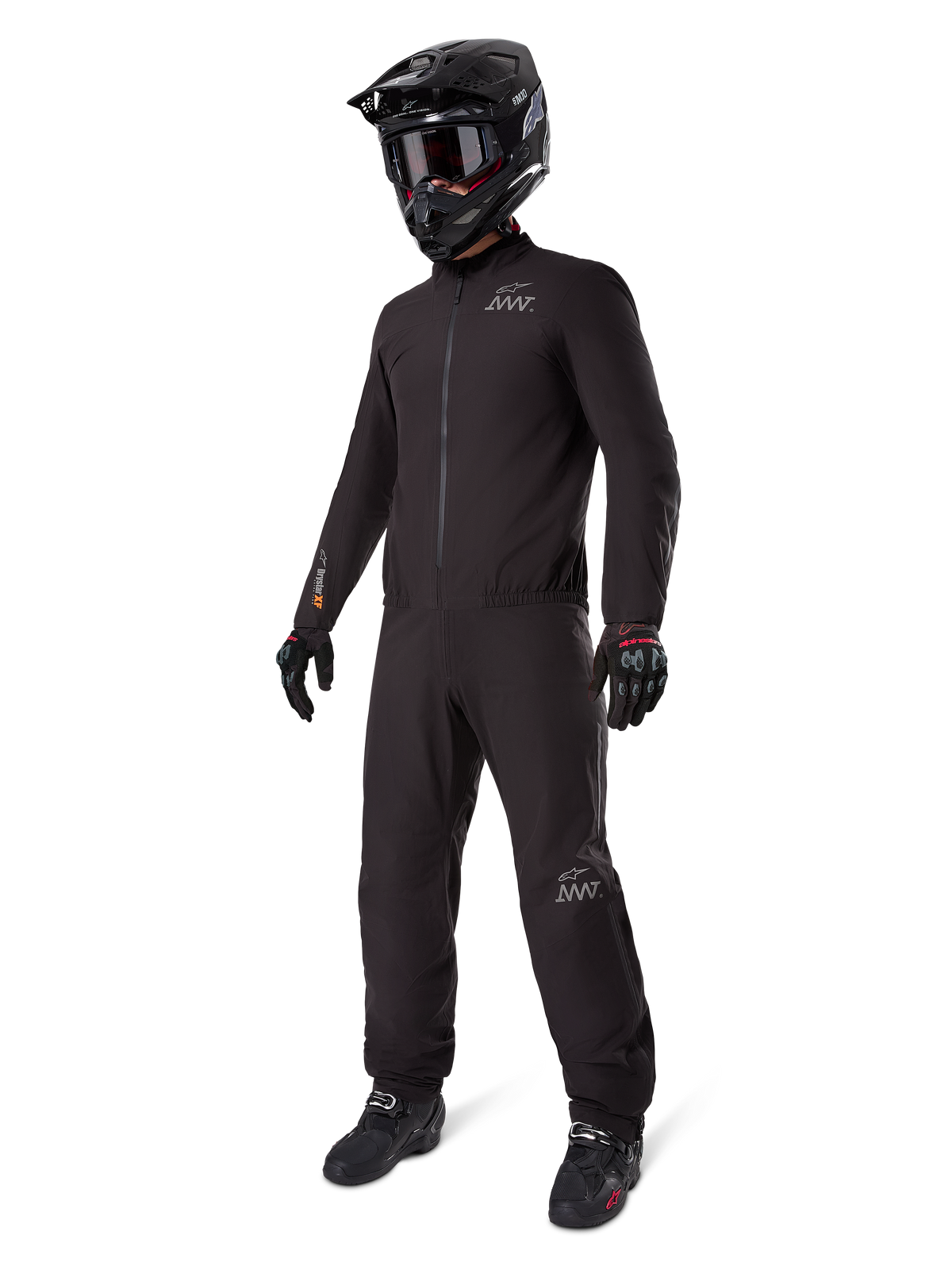 Alpinestars AMT-8 Stretch Drystar XF Liner, pełny czarny kombinezon turystyczny adventure, wodoodporna i wiatroszczelna kurtka i spodnie, zestawiony z czarnym kaskiem adventure, goglami, rękawicami i butami motocyklowymi, z logo AMT oraz Drystar XF na rękawach i nogawkach.