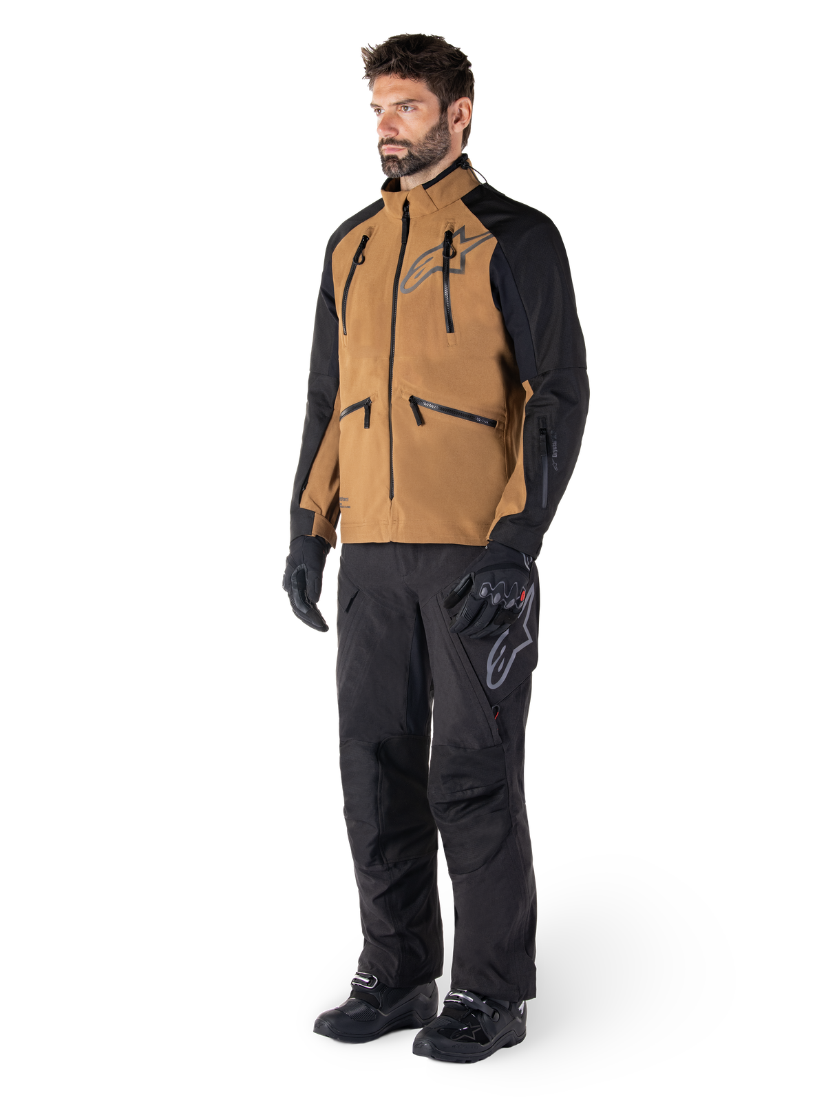 Spodnie Alpinestars Hyde XT Drystar®, motocyklowe spodnie adventure, czarne, zestawione z brązowo-czarną kurtką techniczną, czarnymi rękawicami i butami, konstrukcja typu over-the-boot do jazdy terenowej i dual-sport