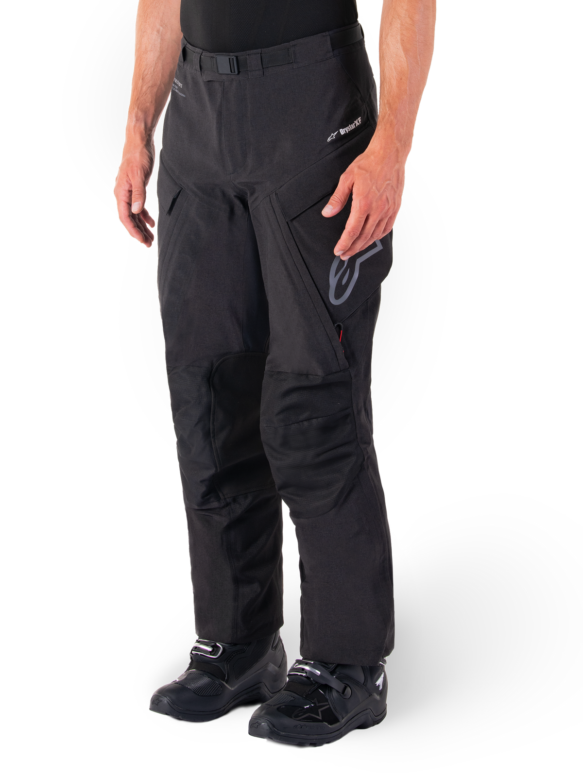 Alpinestars Hyde XT Drystar® Pants, motocyklowe spodnie adventure touring, czarne, zestawione z czarnymi butami, z logo laminowanej membrany Drystar®XF, wzmocnionymi panelami na kolanach i kieszeniami cargo zapinanymi na zamek.