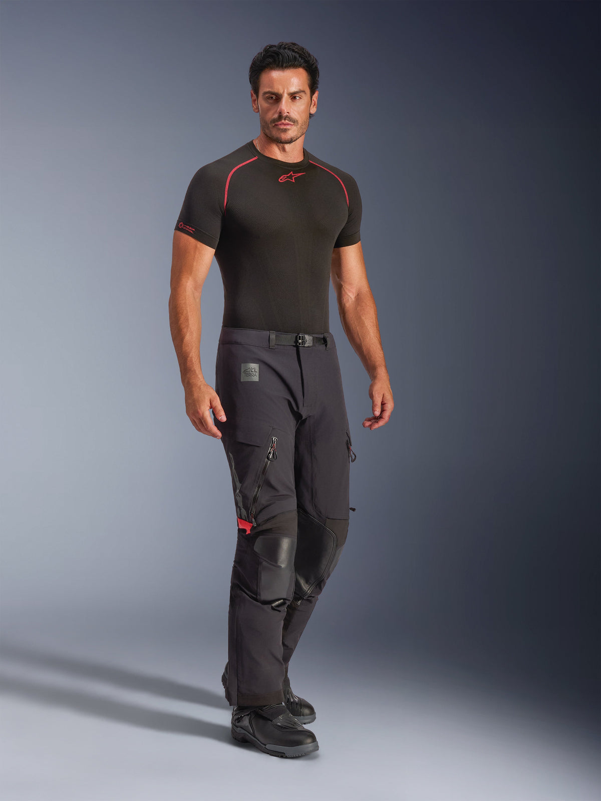 Spodnie Alpinestars Halo Pro Drystar® XF Laminowane, Black Dark Shadow, przygodowe spodnie motocyklowe noszone z czarną warstwą bazową i butami, z dużymi otworami wentylacyjnymi na udach zapinanymi na zamek, skórzanymi wzmocnieniami na kolanach i paskiem z magnetyczną klamrą, zaprojektowane pod kątem wydajności w każdym terenie