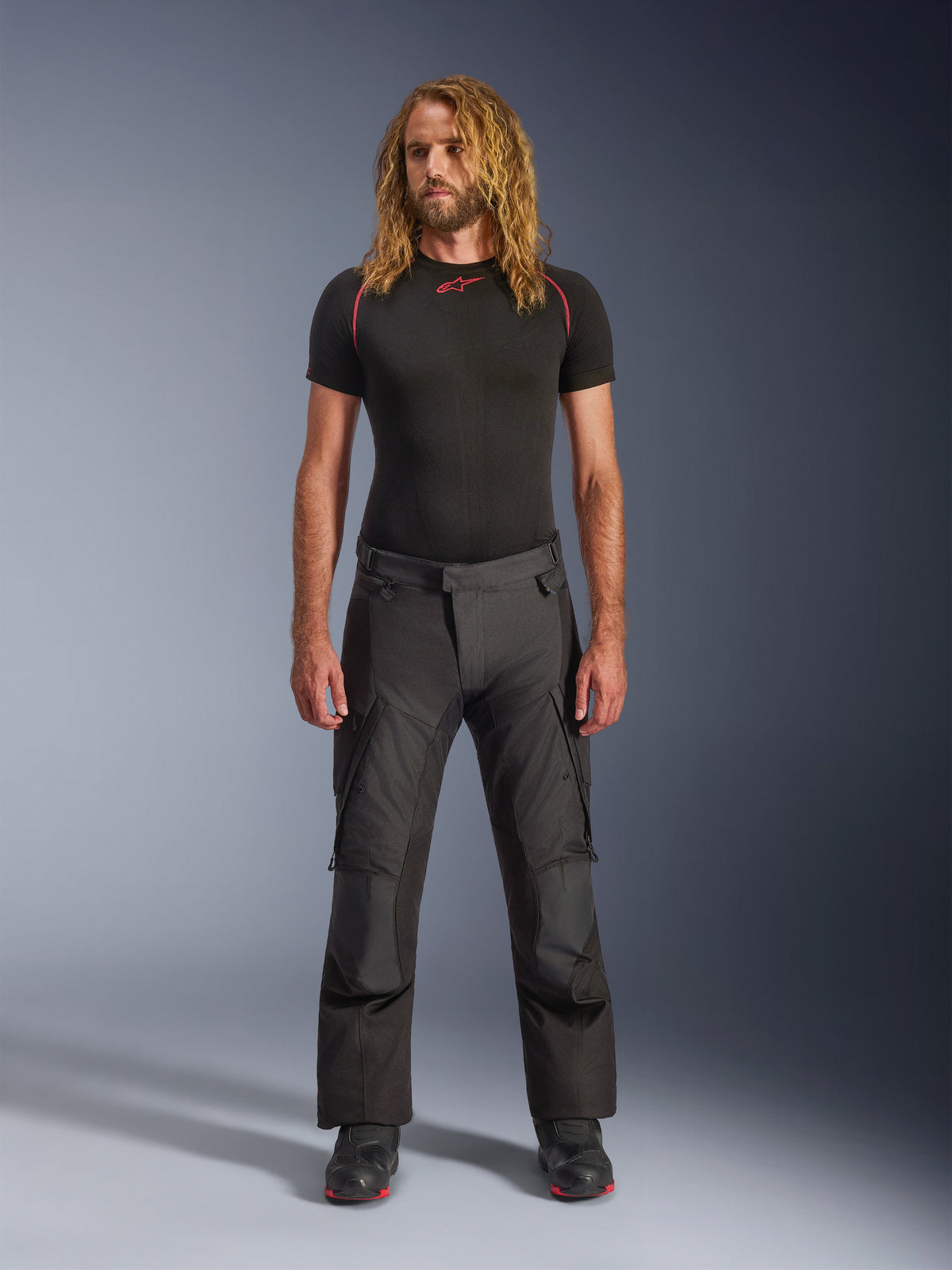 Alpinestars Andes V4 Drystar® Pants, Black adventure motorcycle pants, worn with a black short-sleeved base layer and riding boots, featuring reinforced panels and cargo pockets, durable textile construction for all-weather use