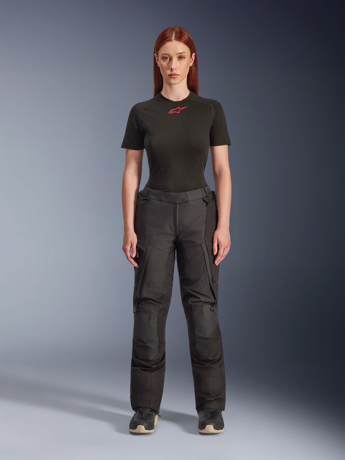 Spodnie Alpinestars Stella Andes V4 Drystar®, czarne damskie spodnie motocyklowe adventure touring, prezentowane na modelce w czarnym t-shircie Alpinestars, techniczny design tekstylny z kieszeniami cargo i wzmocnionymi panelami na kolanach.