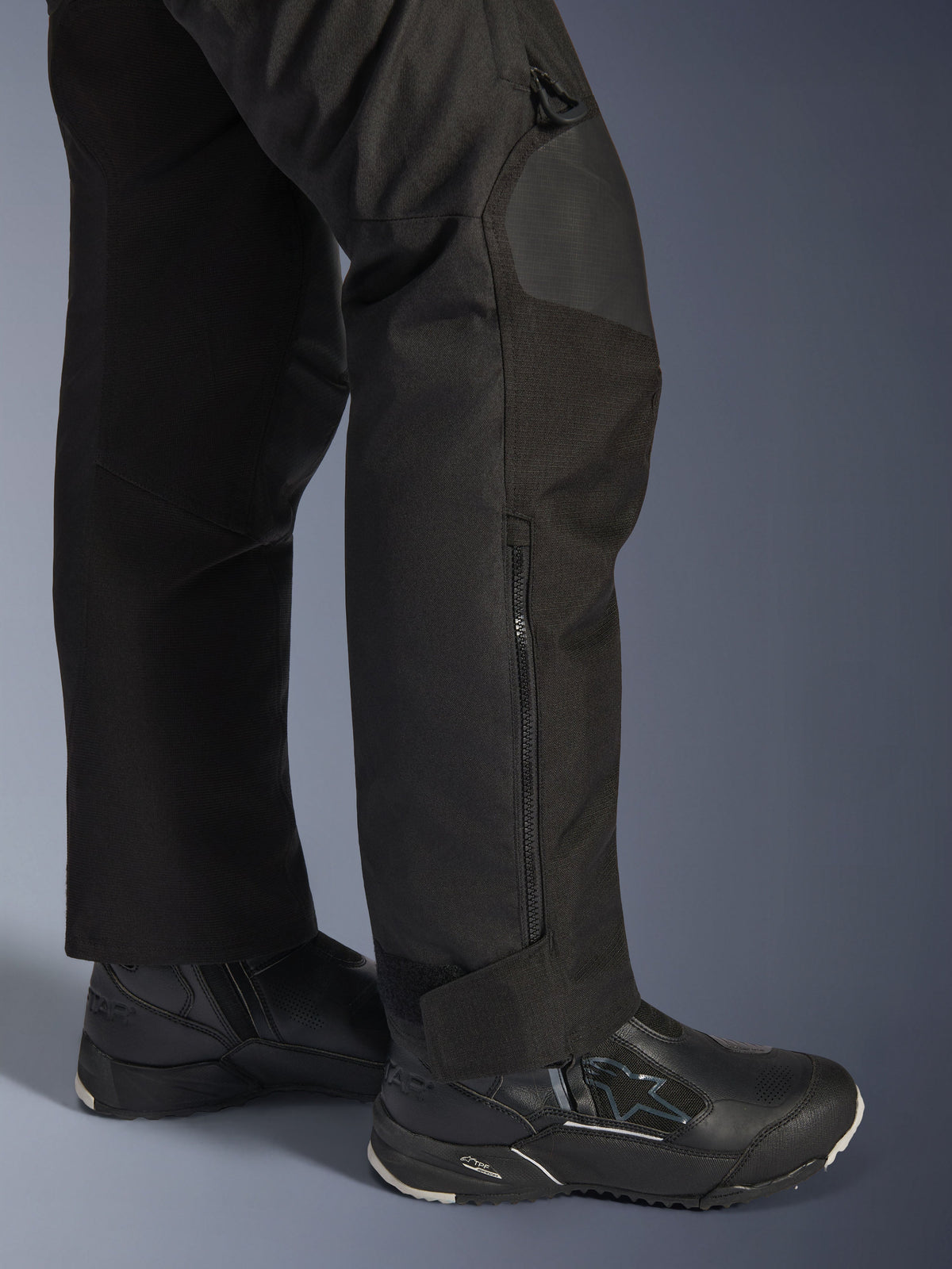 Alpinestars Stella Andes V4 Drystar® Pants, damskie spodnie motocyklowe, czarne, zbliżenie na dolną część nogawki z bocznym zamkiem i regulowanym mankietem przy kostce, noszone z czarnymi butami motocyklowymi Alpinestars