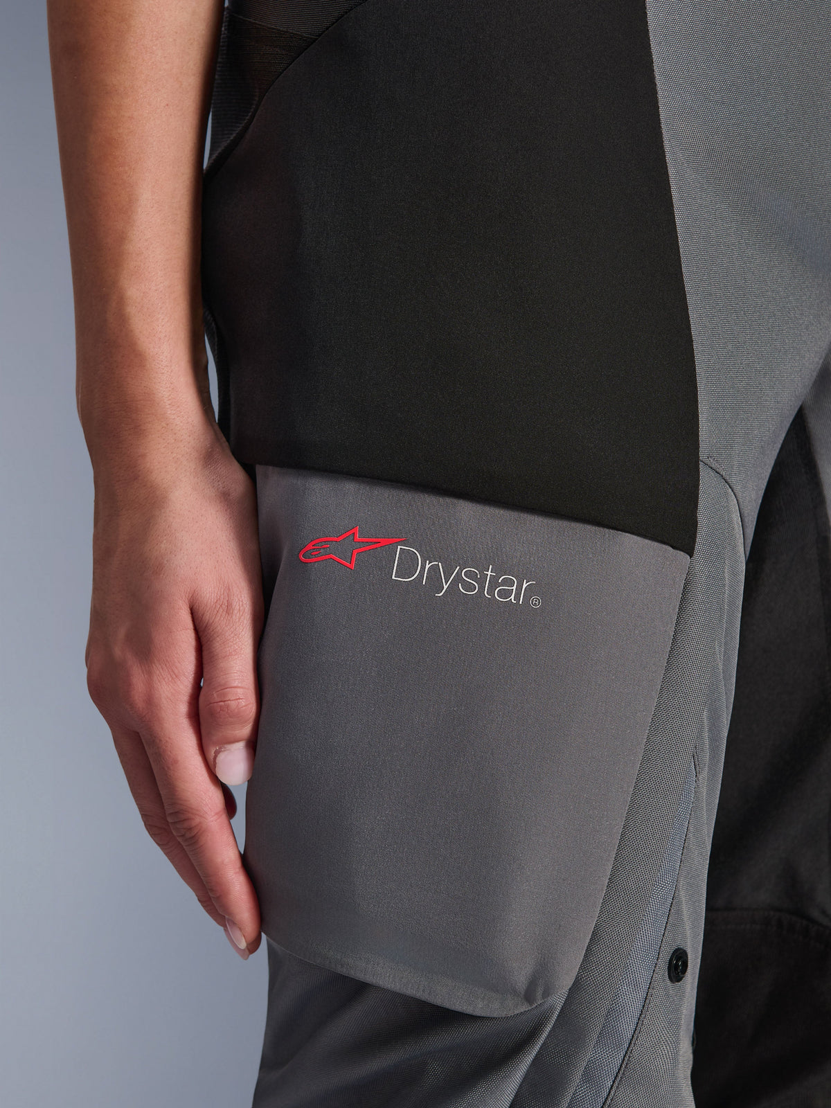 Spodnie Alpinestars Stella Andes V4 Drystar®, damskie spodnie adventure-touring, czarno-ciemnoszare, zbliżenie na okolicę uda pokazujące logo Drystar i czerwoną gwiazdę Alpinestars na wzmocnionych panelach tekstylnych