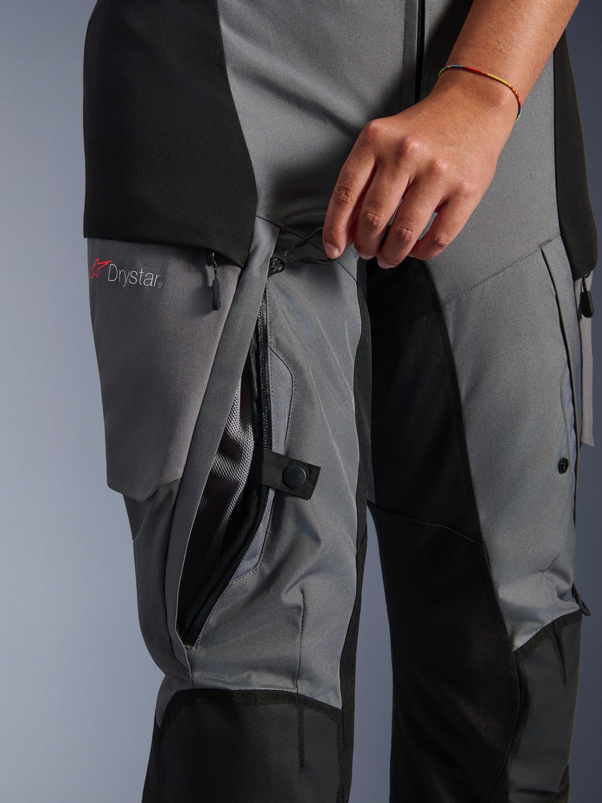 Alpinestars Stella Andes V4 Drystar Pants, czarno-ciemnoszary materiał tekstylny, zbliżenie na zamek bezpośredniej wentylacji na udzie otwierany ręką, widoczna siateczkowa podszewka, logo Drystar, odzież motocyklowa typu adventure