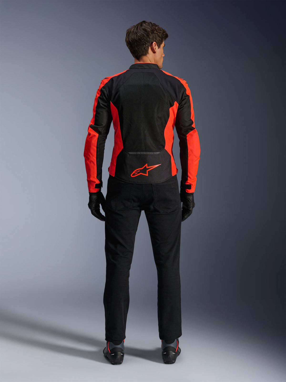 Alpinestars Viper Air V4 Jacket, Red Fluo and Black, back view showing large tech mesh panels and bright red fluorescent side accents, red Alpinestars logo on the lower back, worn with black riding pants and gloves.