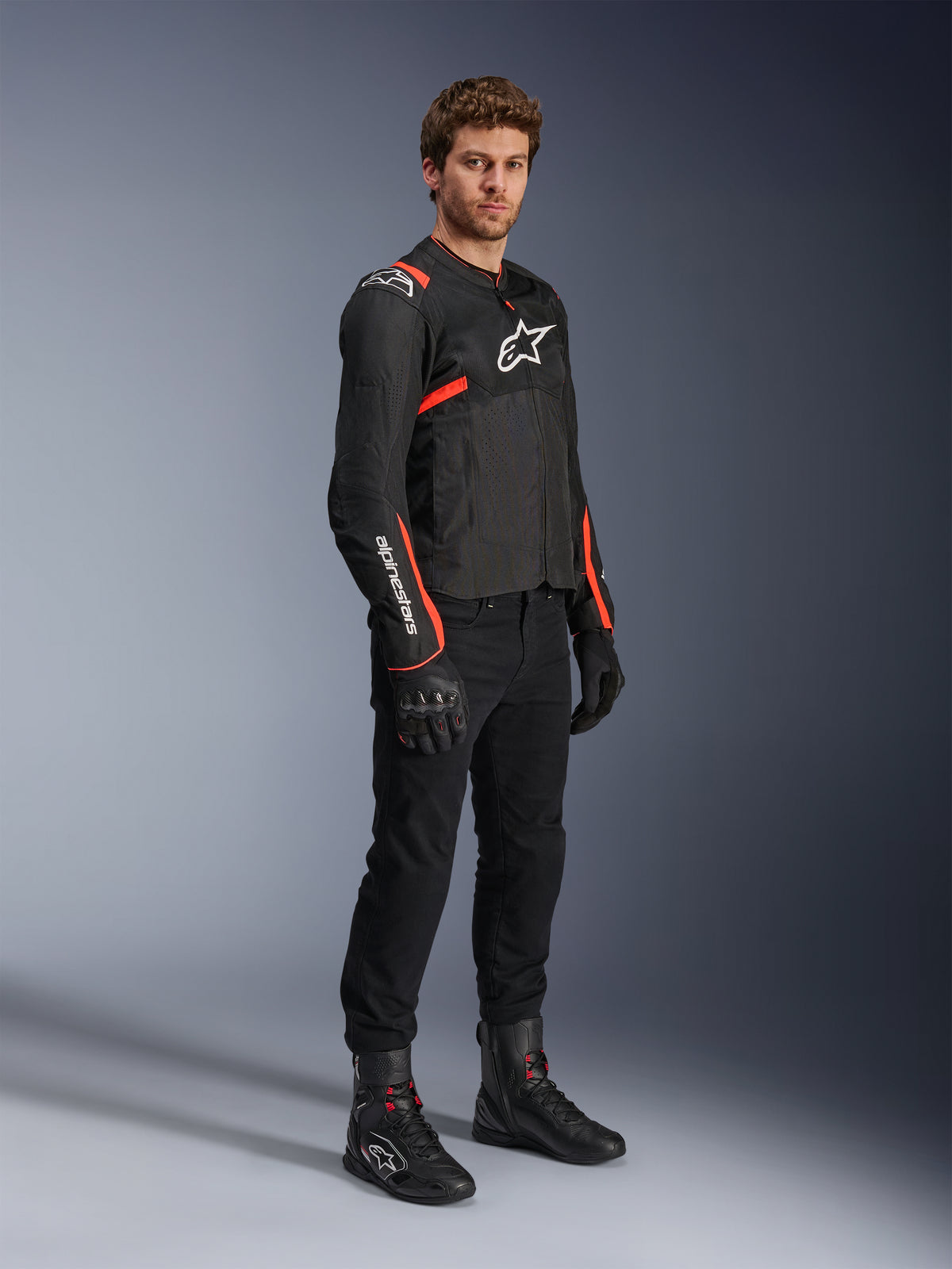 Alpinestars T-SPS Air V2, tekstylna kurtka motocyklowa, wentylowane panele z siatki, męska, czarna i czerwona fluo, model w pełnym stroju.