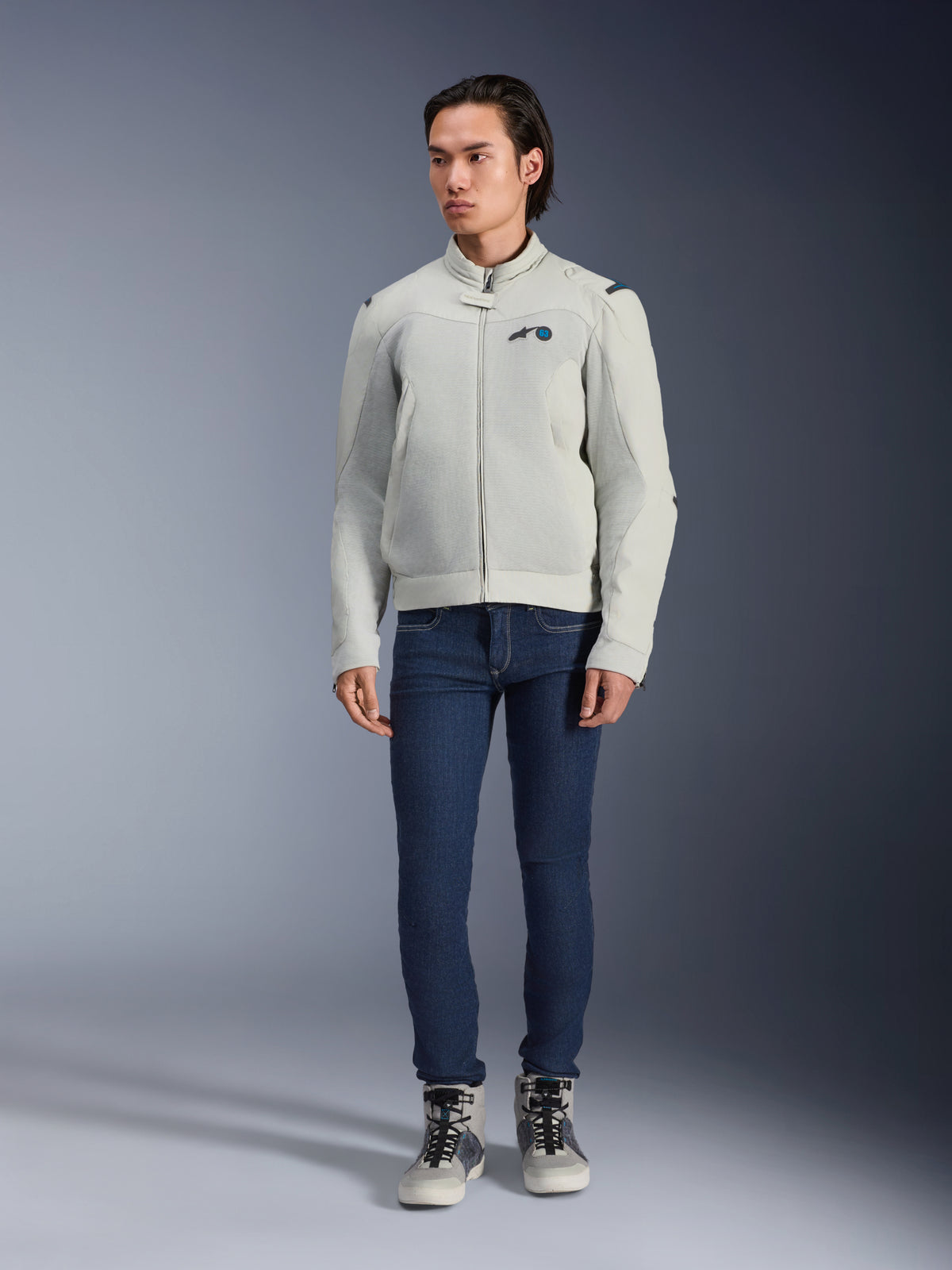 Alpinestars Circal-1 Air Jacket, szara (Metal Gray), miejska kurtka motocyklowa z siatkowymi panelami wentylacyjnymi, prezentowana na modelu w niebieskich jeansach i szarych butach motocyklowych, minimalistyczny design do zrównoważonej jazdy miejskiej.