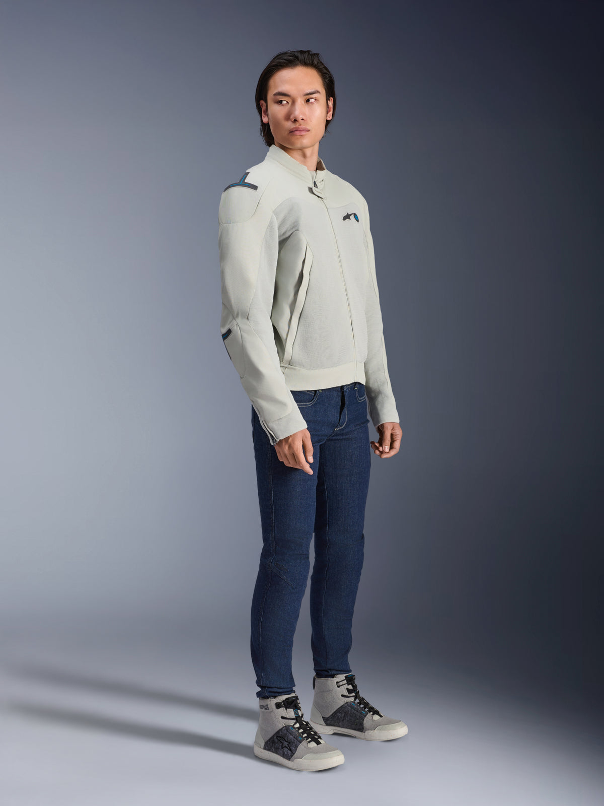 Kurtka Alpinestars Circal-1 Air w kolorze Metal Gray i Methyl Blue, prezentowana przez modela w ciemnoniebieskich jeansach i szarych butach sportowych, miejska letnia kurtka motocyklowa z dużymi panelami wentylacyjnymi z siatki i o minimalistycznym designie.