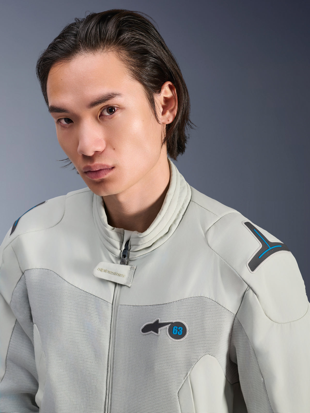 Alpinestars Circal-1 Air Jacket, Metal Gray z akcentami Methyl Blue, męski model w miejskiej letniej kurtce motocyklowej, zbliżenie na siatkowe panele wentylacyjne i minimalistyczny branding na klatce piersiowej