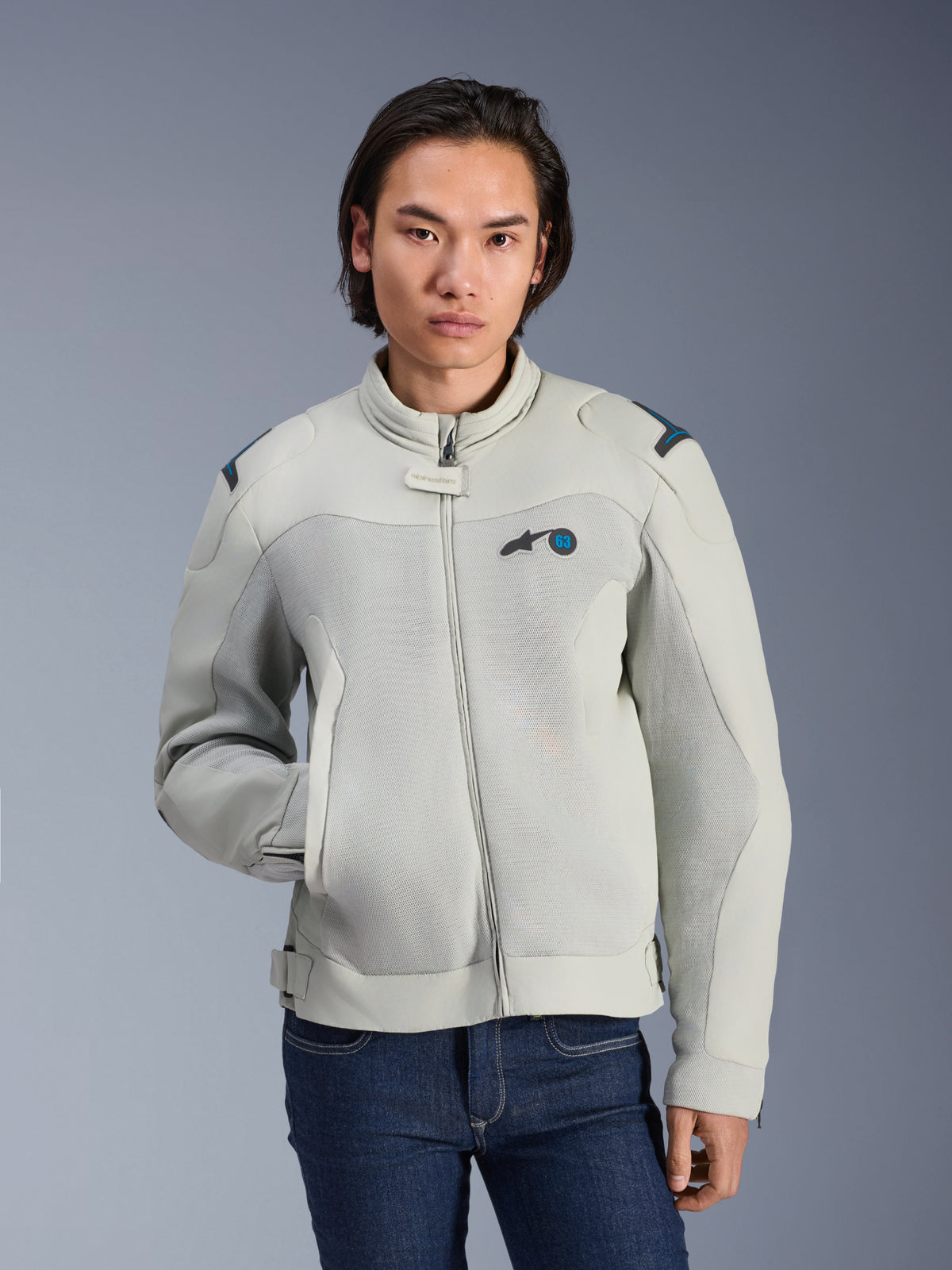 Alpinestars Circal-1 Air Jacket, kolory Metal Gray i Methyl Blue, miejska kurtka motocyklowa z siatkowymi panelami wentylacyjnymi, zapięcie na zamek i wyściełany kołnierz, noszona przez modela w niebieskich dżinsach, futurystyczny i zrównoważony design na letnią jazdę
