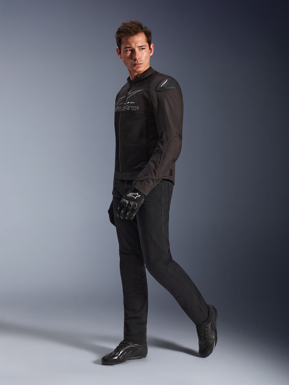 Kurtka Alpinestars SMX Air w kolorze Black Anthracite, model ubrany w pasujące czarne spodnie motocyklowe, rękawice i buty, studyjne ujęcie całej sylwetki, sportowa odzież motocyklowa z siatki technicznej i sliderami na ramionach