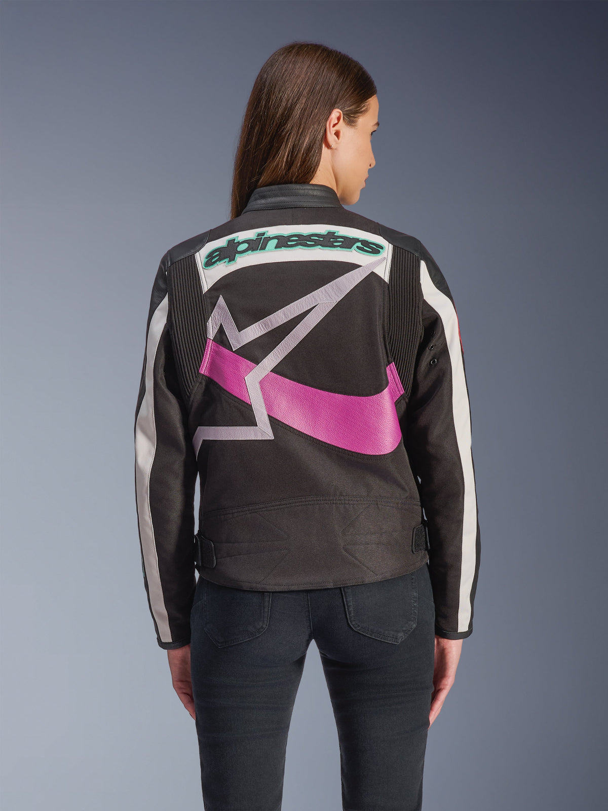 Damska kurtka Alpinestars Idles, widok z tyłu, czarna, złamana biel i fiolet, duże graficzne logo z gwiazdą na plecach, morski haftowany napis, panele akordeonowe na ramionach, miejska odzież motocyklowa inspirowana stylem vintage