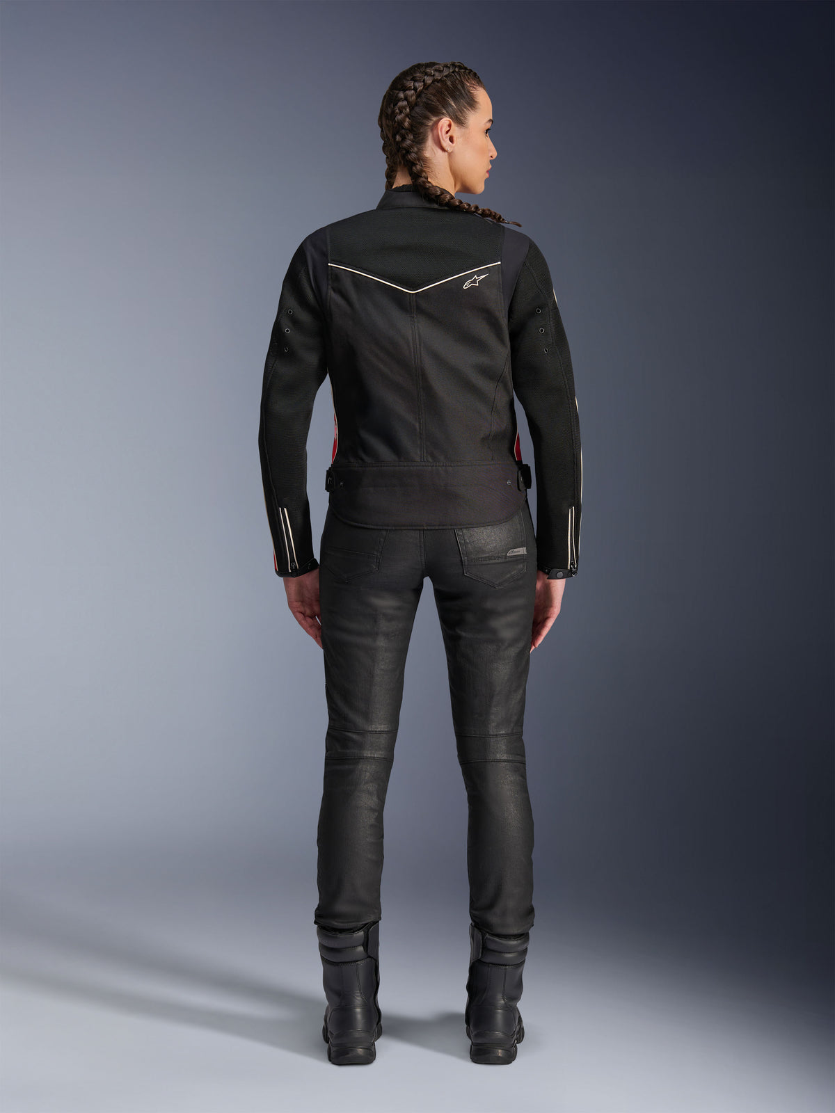 Alpinestars Stella T-Dyno Air Jacket, widok z tyłu, czarna damska kurtka motocyklowa z białymi lamówkami i małym logo gwiazdy, noszona z czarnymi spodniami technicznymi i butami motocyklowymi, dopasowany fason motocyklowy do miejskiej jazdy szosowej