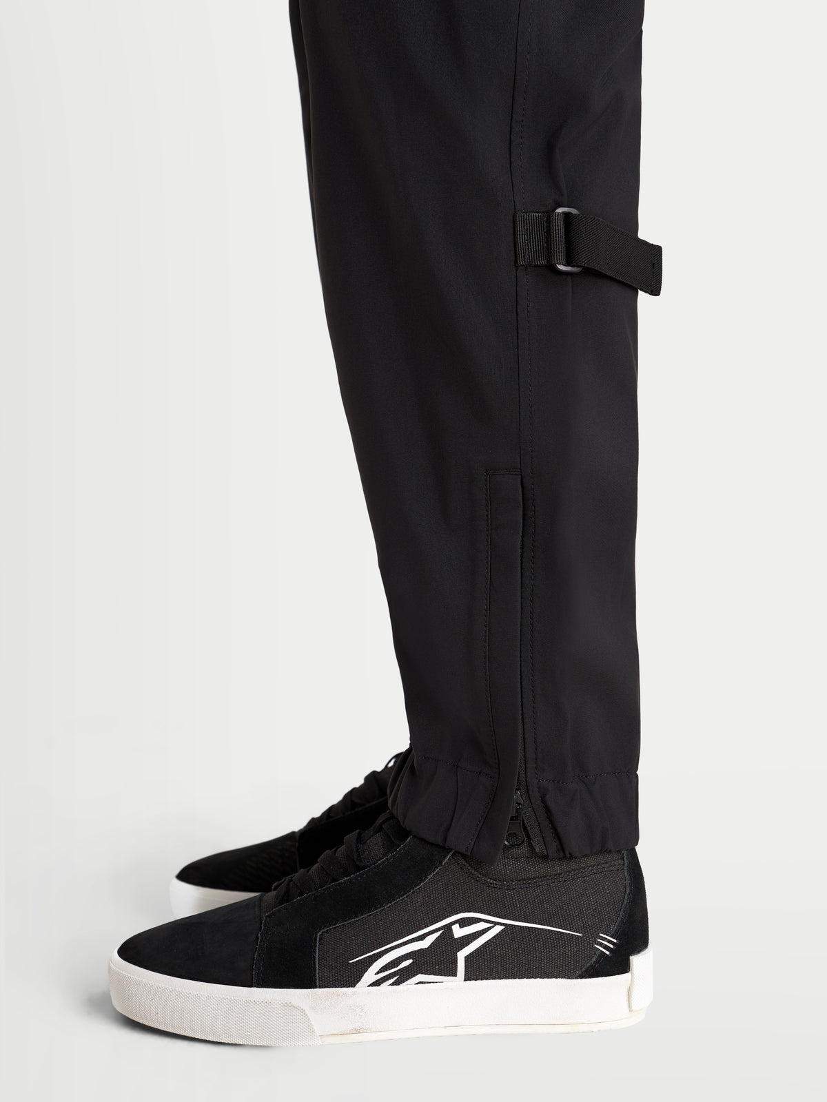 Alpinestars Juggernaut V2 Drystar spodnie motocyklowe miejskie męskie, czarne, zbliżenie z boku na regulację dolnej nogawki i elastyczny dół z zamkiem błyskawicznym