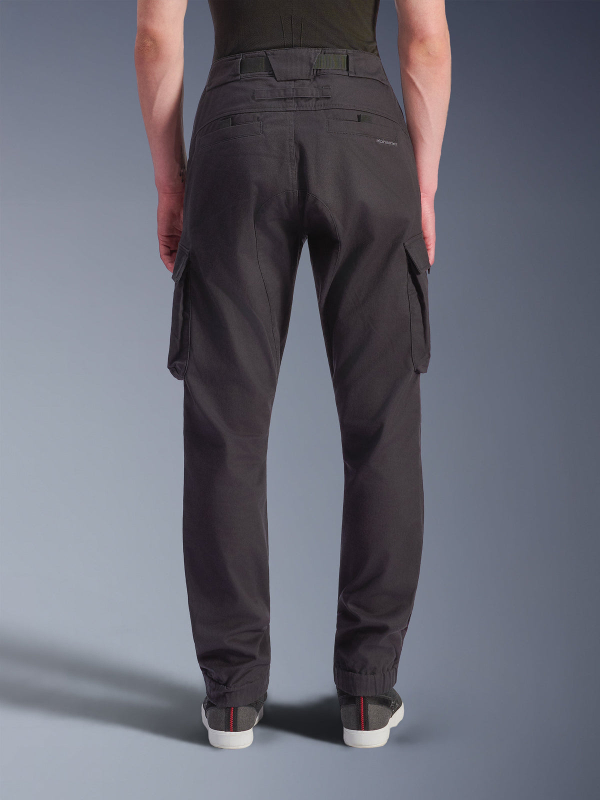 Alpinestars Flex-AST Cargo Pants, czarne, widok od tyłu technicznych spodni motocyklowych o regularnym, zwężanym kroju z elastycznymi mankietami, wyposażone w duże kieszenie cargo i subtelne logowanie, zaprojektowane do jazdy miejskiej.