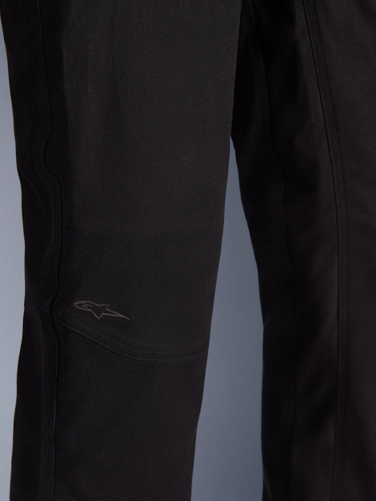 Alpinestars Flex-AST Canvas Pants, miejskie spodnie motocyklowe, czarne, zbliżenie na okolicę kolan z wyprofilowanymi panelami i subtelnym haftowanym logo na wytrzymałej tkaninie canvas.