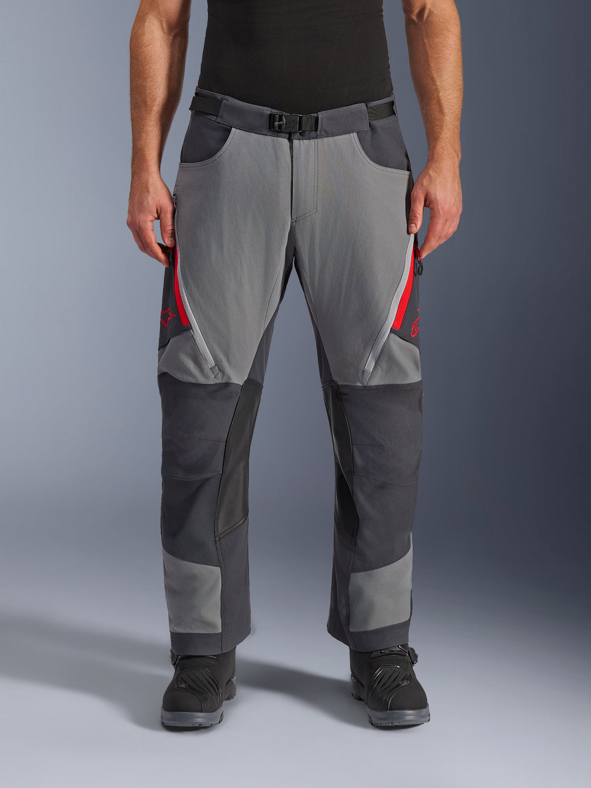 Alpinestars Maxdura Dual Pants, spodnie motocyklowe adventure, ciemnoszare i szare z czerwonymi akcentami, widok z przodu, zapinane na zamek otwory wentylacyjne na udach, pasek z magnetyczną klamrą i wzmocnione panele na kolanach, krój na buty do jazdy dual-sport