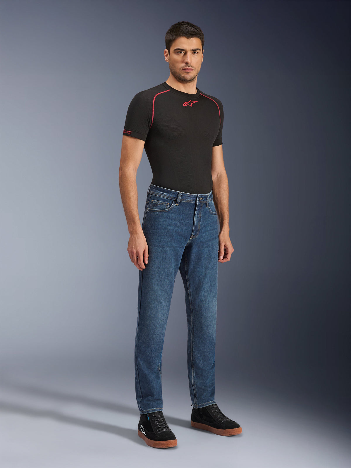 Alpinestars Flex-AST 5 Denim Pants, Indigo Washed motorcycle jeans, modern tapered fit, worn by a male model with a black performance t-shirt and black sneakers, casual urban riding apparel.