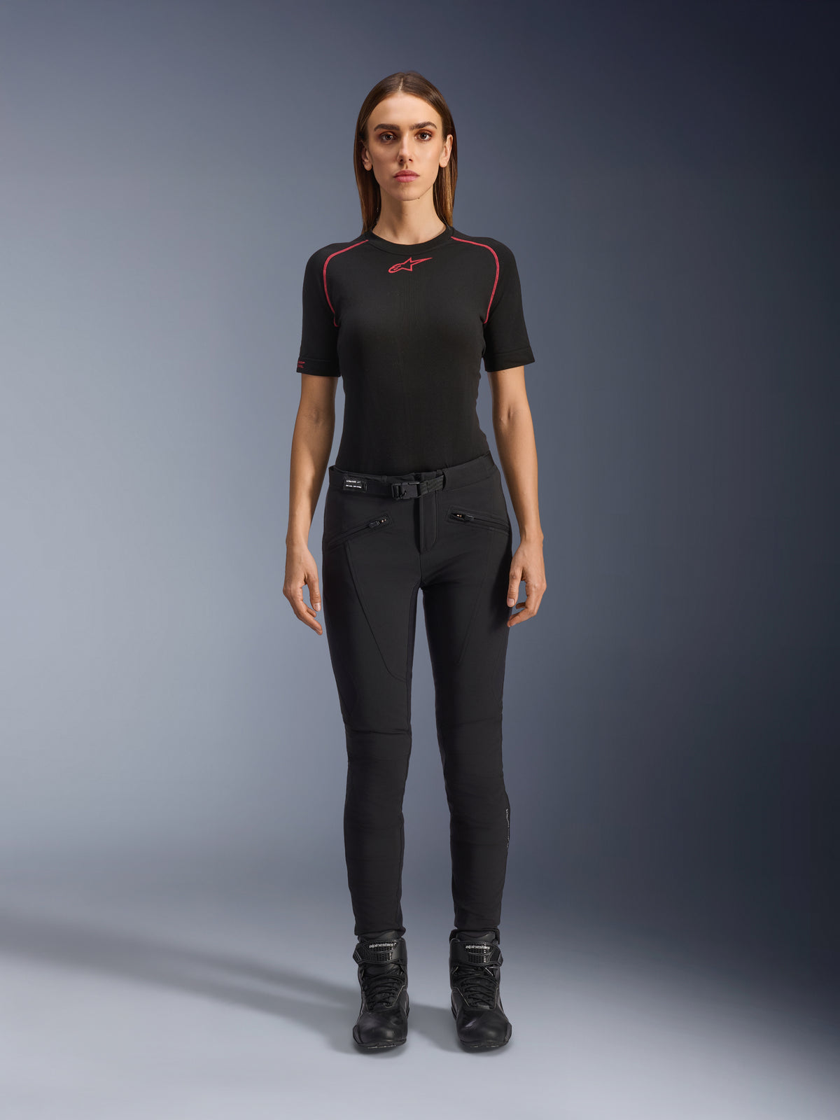 Alpinestars Alamosa Women Pants, czarne dopasowane spodnie motocyklowe, zaprezentowane na modelce przodem, z przednimi kieszeniami na zamek i zintegrowanym paskiem w talii, minimalistyczny styl inspirowany streetwearem do jazdy miejskiej
