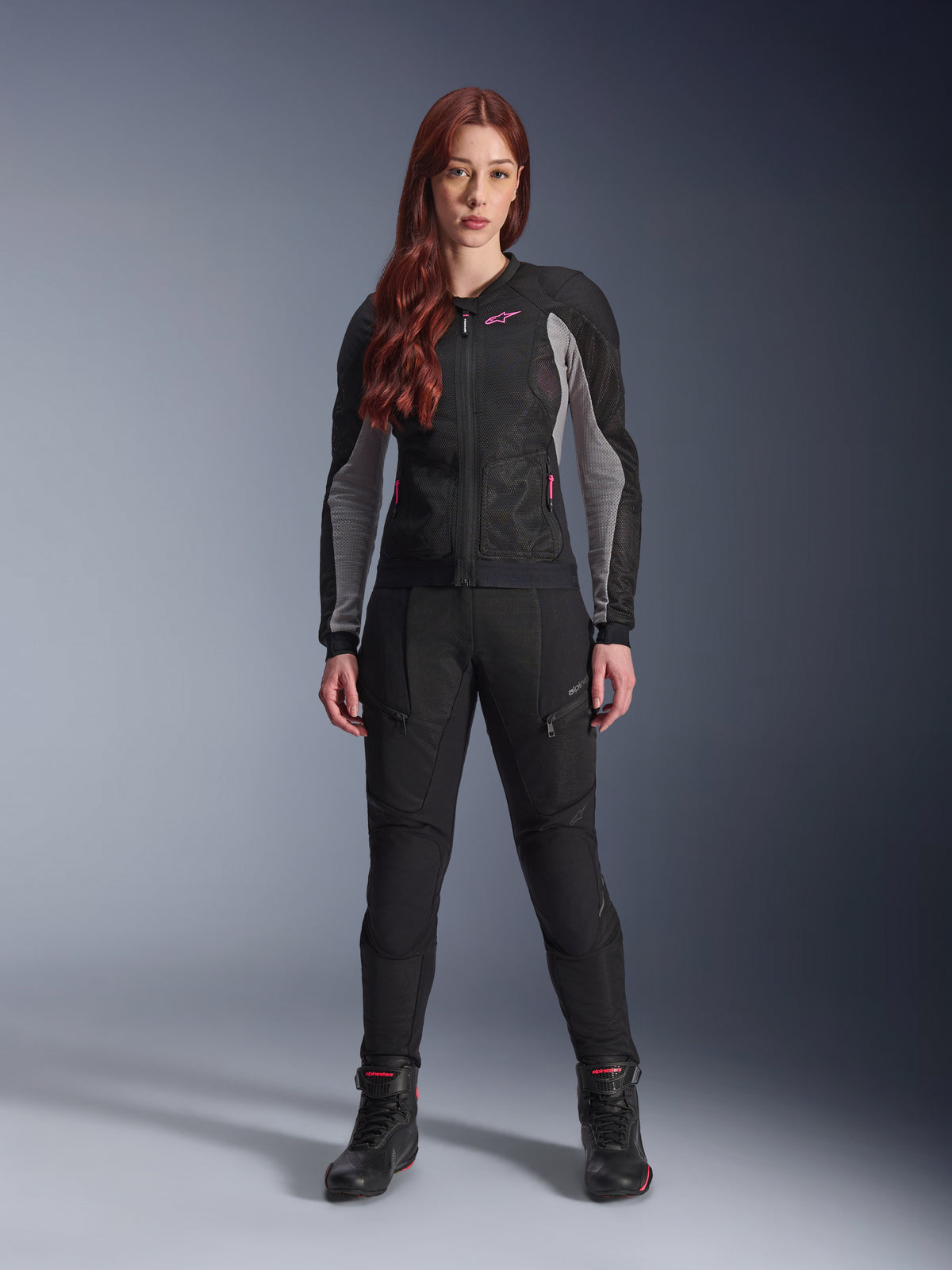 Alpinestars Stella Troop-Air Pants, damskie spodnie motocyklowe w kolorze czarnym, wyposażone w panele z siatki i kieszenie na zamek, stylizacja z dopasowaną czarno-szarą kurtką z siatki z różowymi akcentami i czarnymi butami motocyklowymi, kompletny miejski strój motocyklowy.