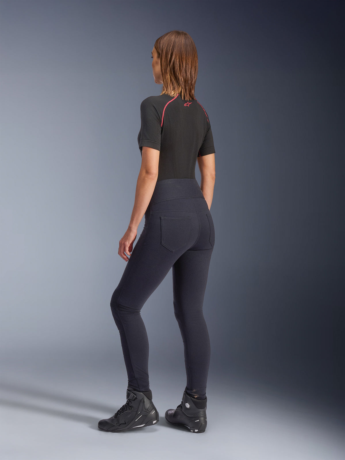 Alpinestars Stella Flex-Ast Leggings, damskie legginsy motocyklowe, czarne, widok z tyłu prezentujący wysoki stan i tylne kieszenie, zestawione z czarną warstwą bazową z krótkim rękawem i czerwonymi akcentami oraz czarnymi butami motocyklowymi, współczesna miejska odzież motocyklowa