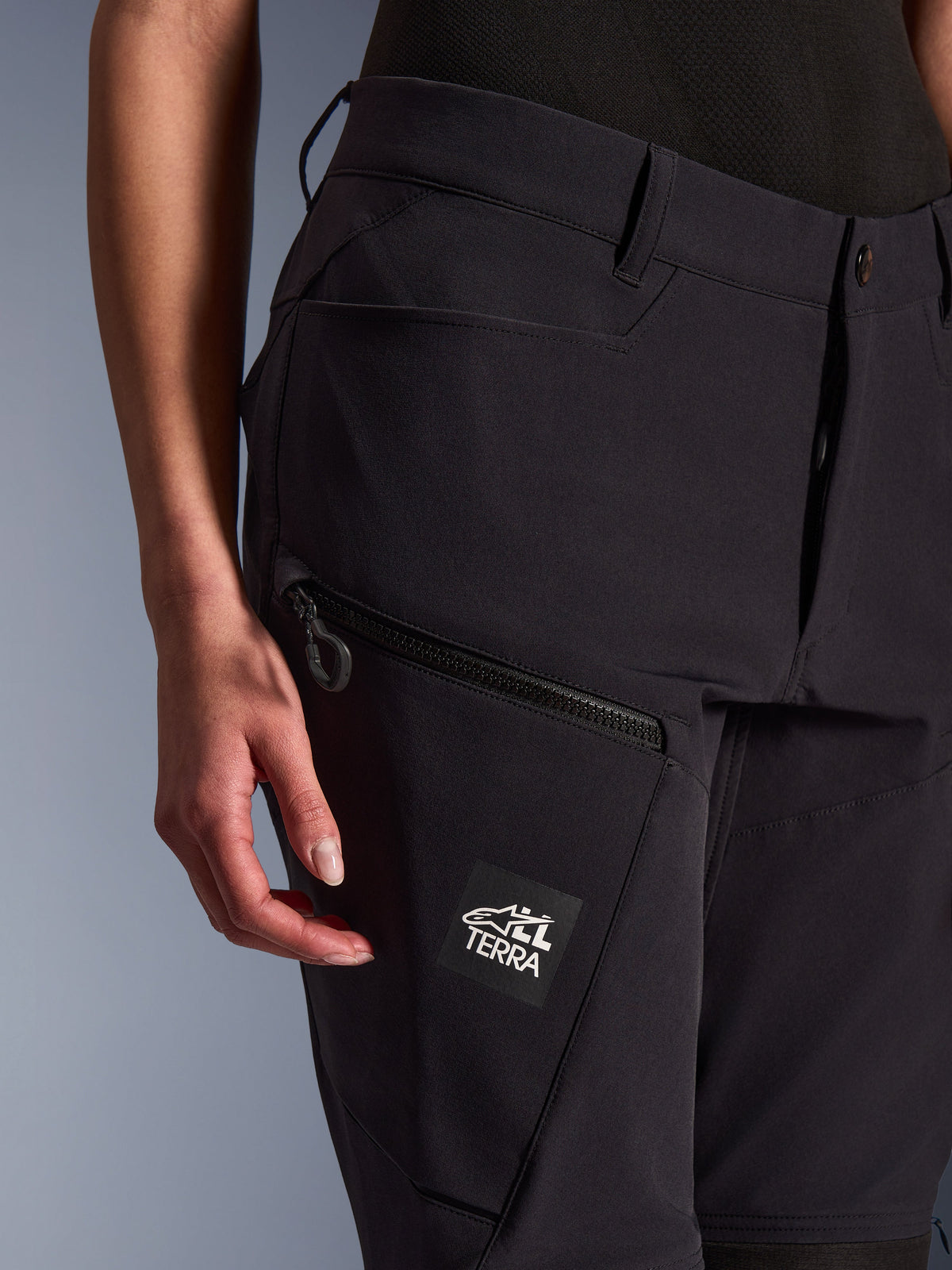 Alpinestars Woman Stella Flex-AST Explorer Pants, Black, close-up view showing zippered thigh pocket and ALL TERRA branding patch, lightweight stretch textile for women's adventure motorcycle riding