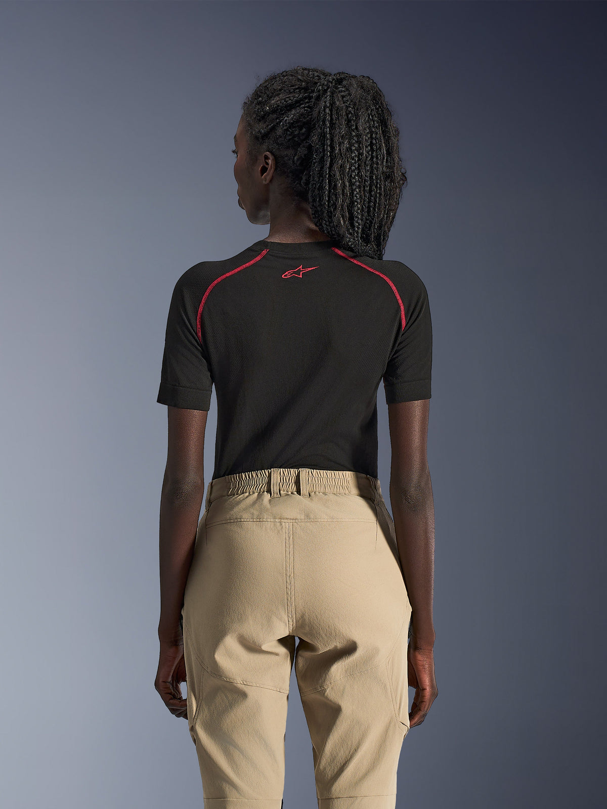Alpinestars Stella Flex-AST Explorer Pants, piaskowe damskie spodnie motocyklowe adventure, widok z tyłu, zestawione z czarną warstwą bazową z krótkim rękawem i czerwonymi akcentami, elastyczny pas i trwała konstrukcja tekstylna