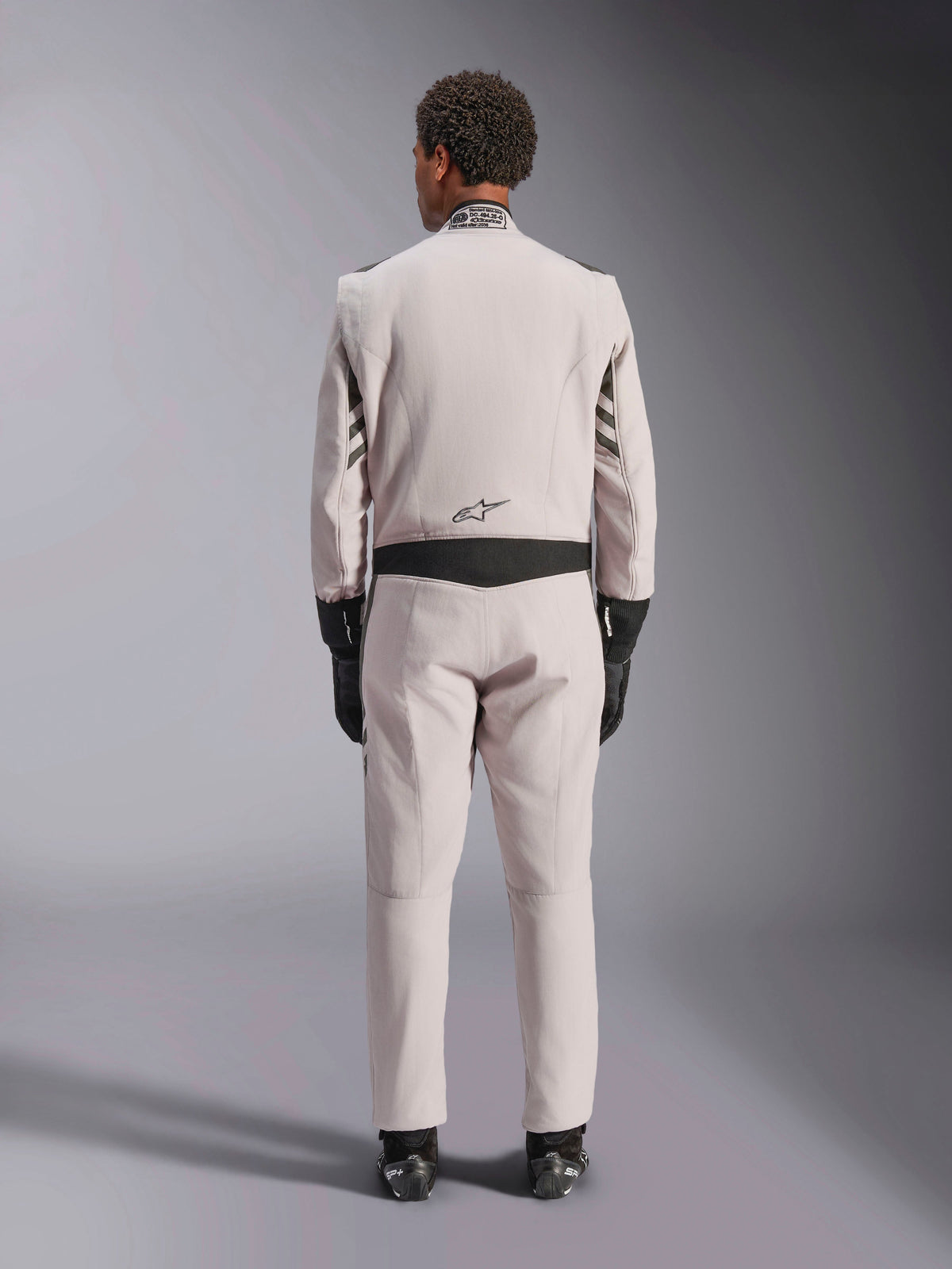 Alpinestars GP Race V3 Suit FIA, Silver Anthracite, back view of one-piece auto racing suit worn with black gloves and boots, featuring black stretch panels on the waist and sleeves, professional motorsport design