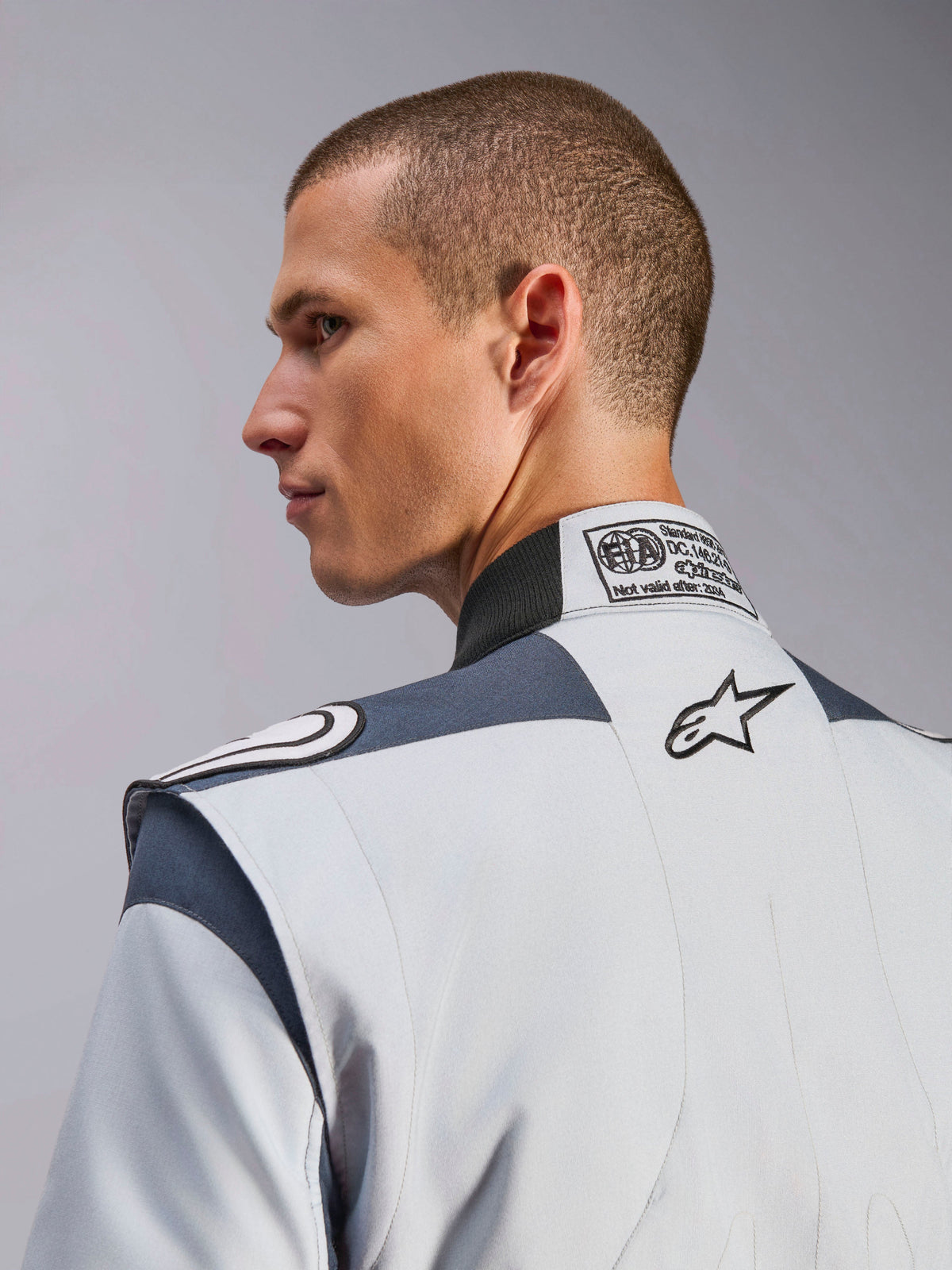 Kombinezon Alpinestars GP Pro Comp V2 - FIA, srebrny i szary, certyfikat FIA i haftowane logo na plecach.