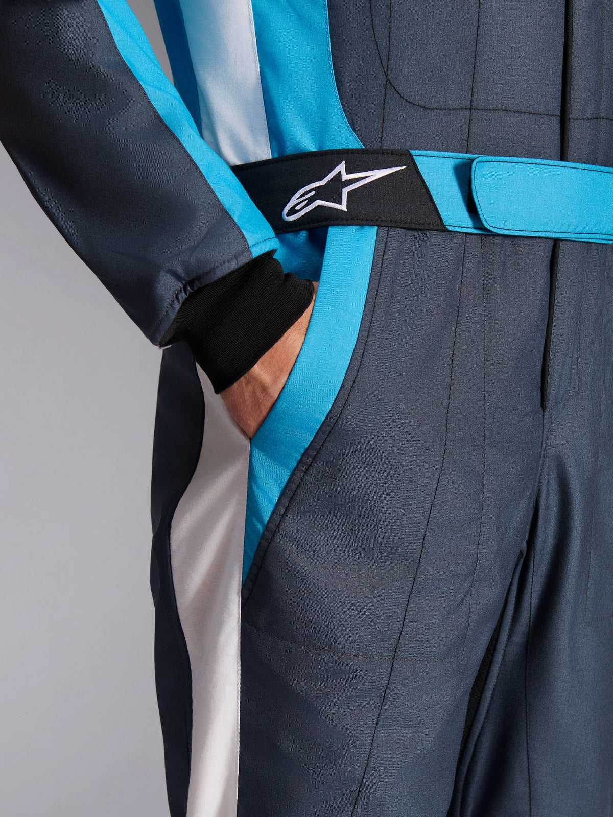 Alpinestars GP Pro Comp V2 FIA Suit in Asphalt and Cyan, featuring a logo belt and side pocket for auto racing.