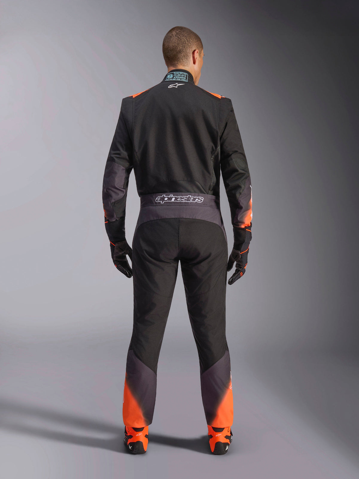 Kombinezon Alpinestars KMX-5 V3, męski kombinezon kartingowy, czarny i pomarańczowy fluo, certyfikat FIA, widok tyłu z logo.