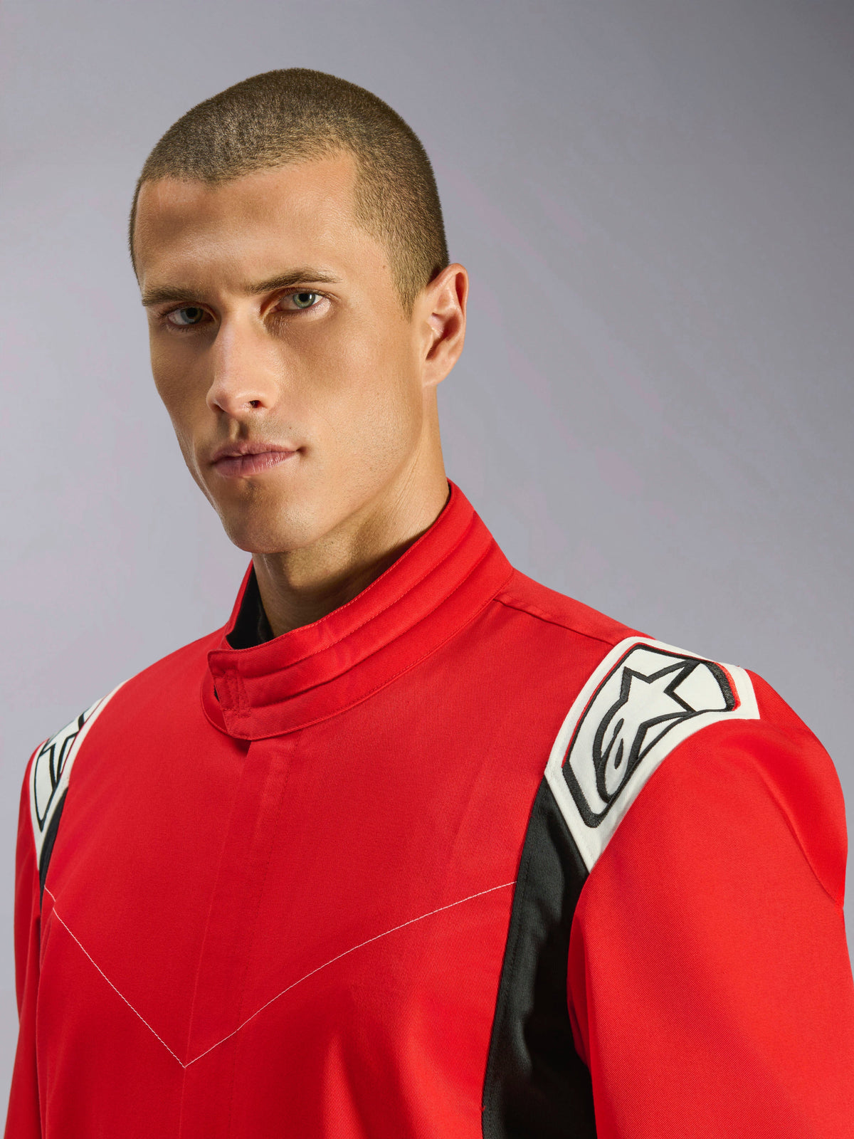Alpinestars Kart Indoor V2 Suit w kolorze czerwonym, zbliżenie portretowe męskiego modela w kombinezonie, podkreślające ergonomiczny kołnierz oraz biało-czarne akcenty na ramionach z logo Alpinestars.