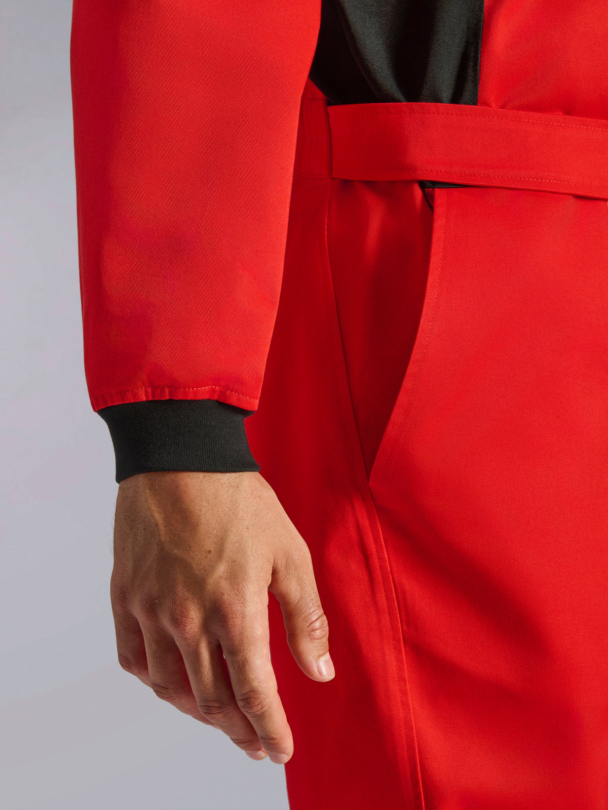 Kombinezon Alpinestars Kart Indoor V2, czerwony kombinezon kartingowy, zbliżenie na czarny dzianinowy mankiet, regulowany pasek w talii i wytrzymały jednowarstwowy materiał o splocie skośnym