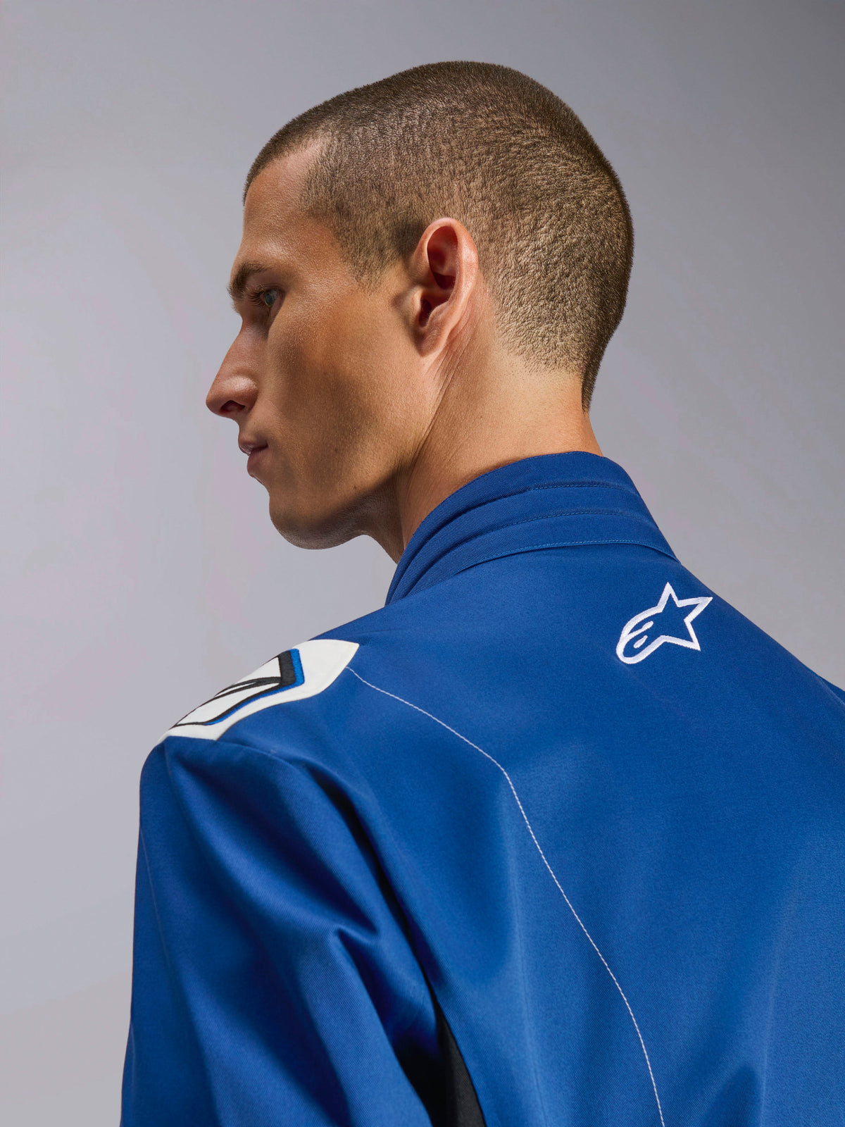 Alpinestars Kart Indoor V2 Suit, niebieski kombinezon kartingowy, zbliżenie z profilu na ergonomiczny kołnierz i górną część pleców z białym logo gwiazdy, ramiona inspirowane Formułą 1, trwała konstrukcja z kepru polibawełnianego