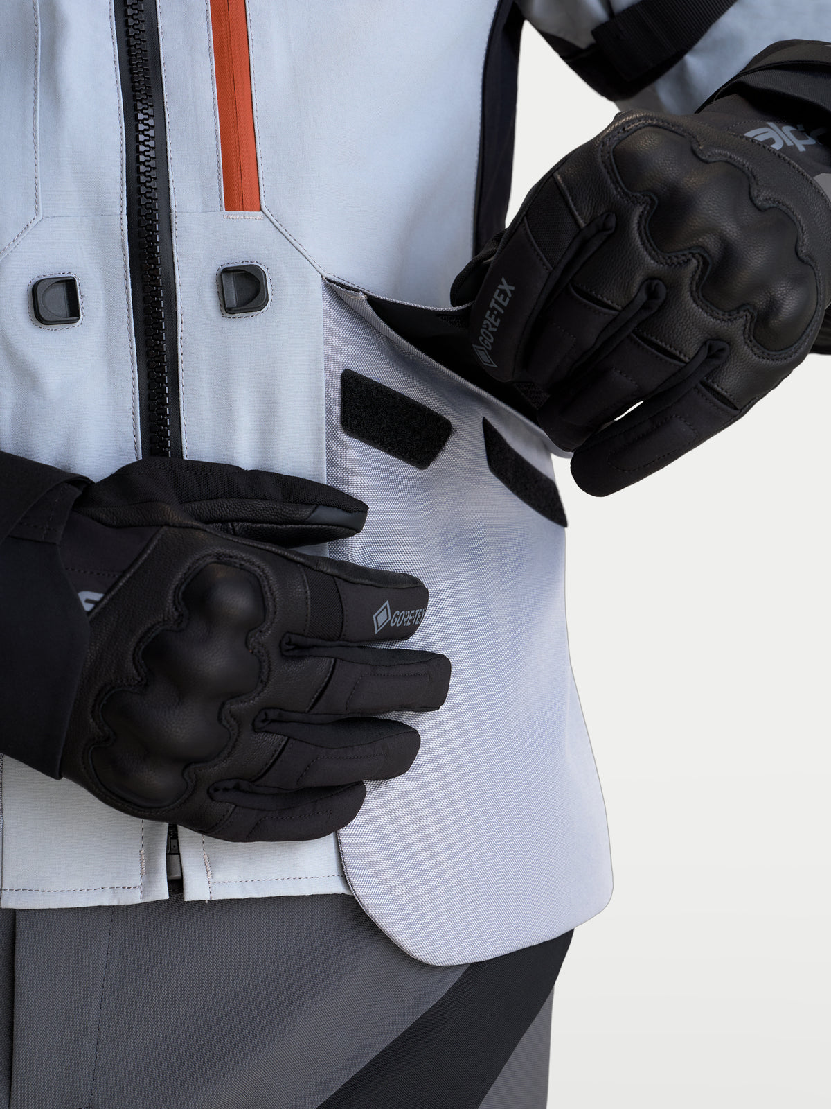 Alpinestars St-7 V2 2L Gore-Tex kurtka motocyklowa adventure, jasnoszara i czarna, zbliżenie na motocyklistę otwierającego panel wentylacyjny w laminowanej powłoce wodoodpornej w czarnych rękawicach