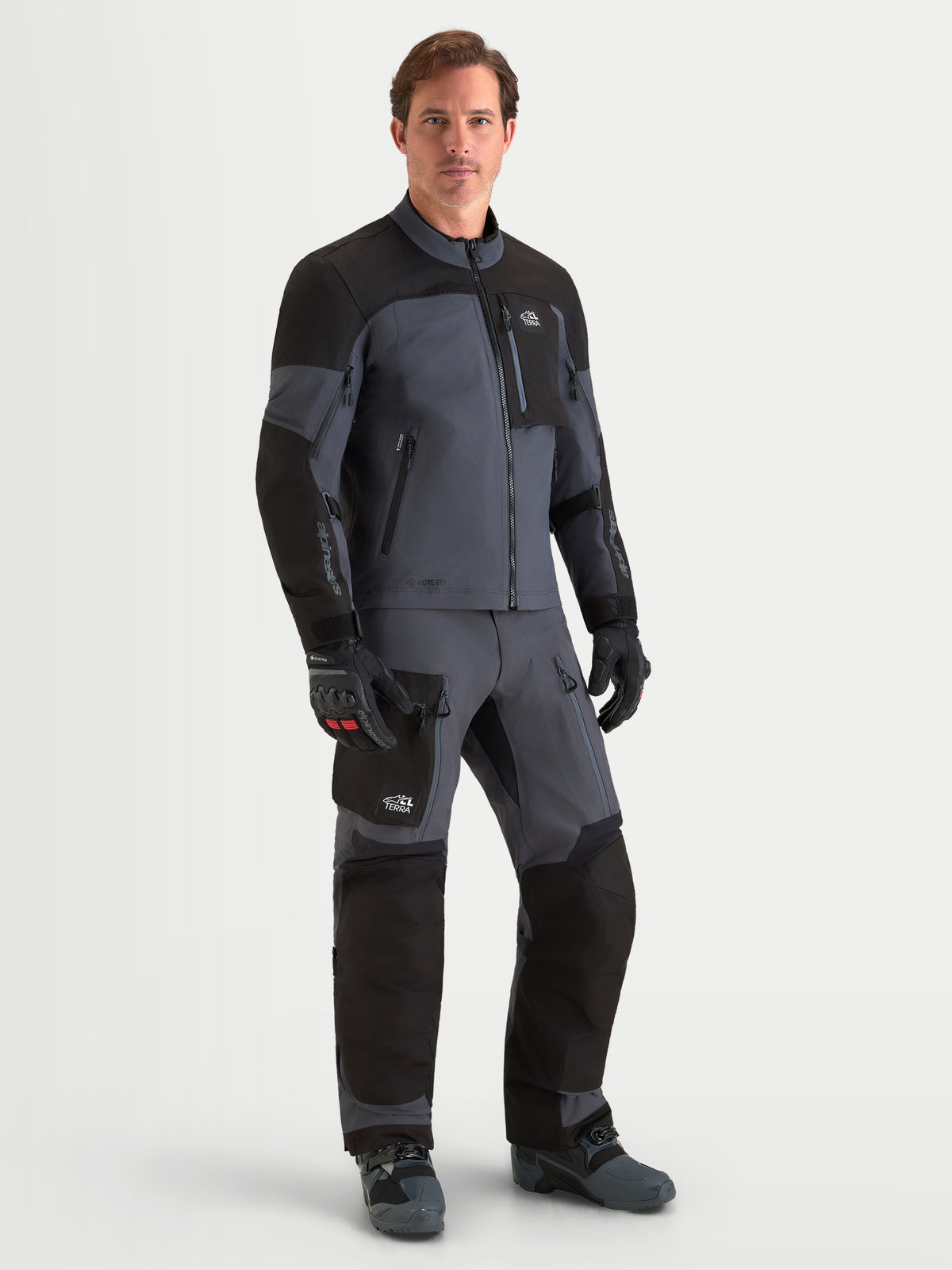 Alpinestars Arenis Gore-Tex Gear Set, męski zestaw motocyklowy adventure kurtka i spodnie w kolorze czarnym i ciemnoszarym, widok z przodu na modelu w pasującej wodoodpornej odzieży tekstylnej
