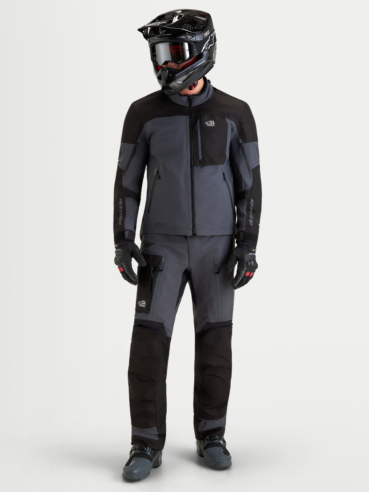 Alpinestars Arenis Gore-Tex Jacket, men's adventure touring motorcycle jacket in black and deep gray, worn by a rider with a matching helmet and protective gear, front full-body view.