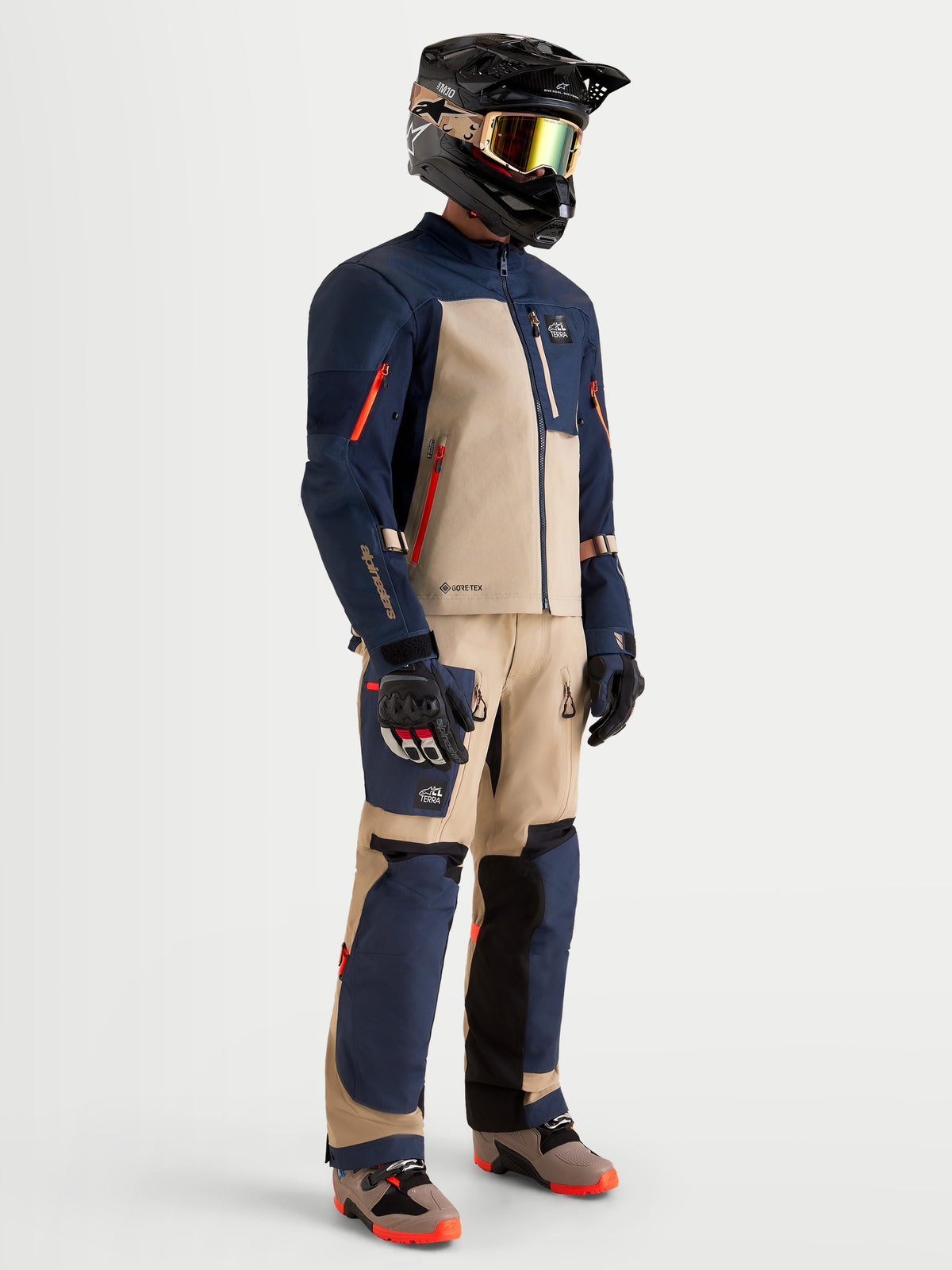 Alpinestars Arenis Gore-Tex kurtka motocyklowa adventure męska w kolorze granatowym i aluminiowym, na modelu w pełnym dopasowanym ekwipunku z kaskiem, goglami i rękawicami