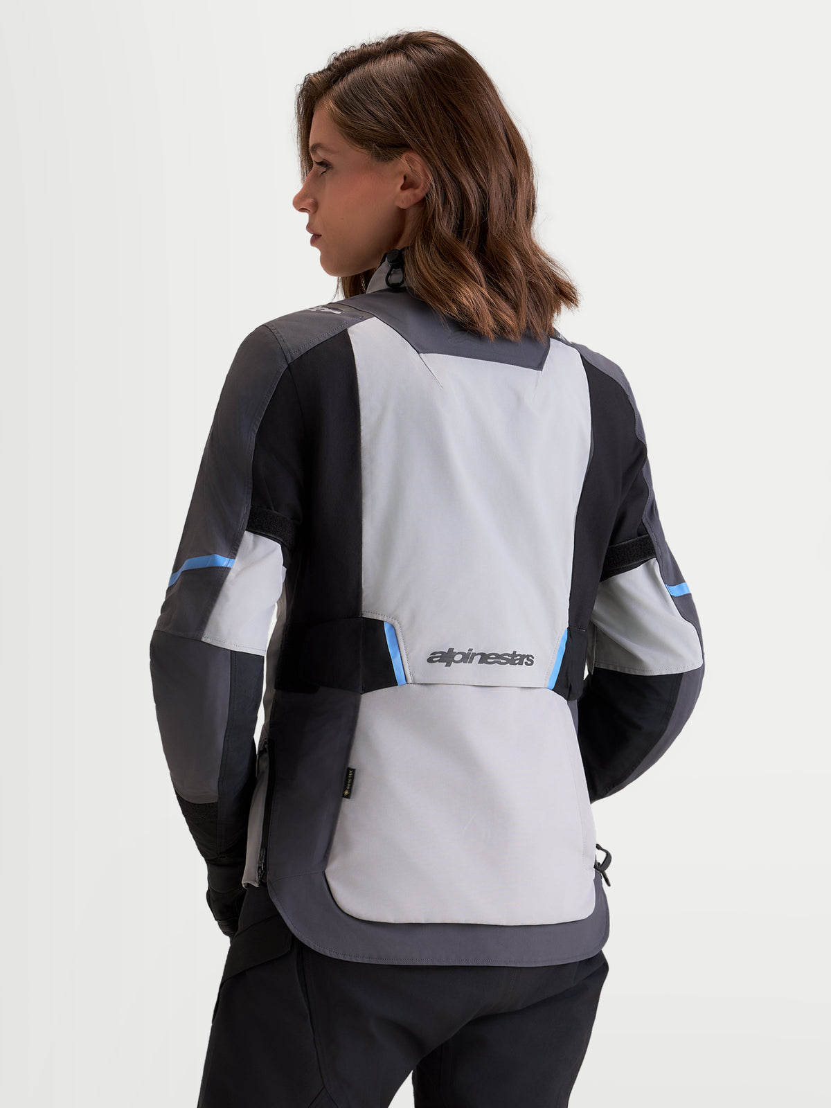 Alpinestars Stella ST-7 V2 2L Gore-Tex kurtka motocyklowa damska adventure, średnio szara, ciemnoszara i czarna, widok z tyłu na wodoodporną konstrukcję tekstylną i branding Alpinestars prezentowaną przez modelkę