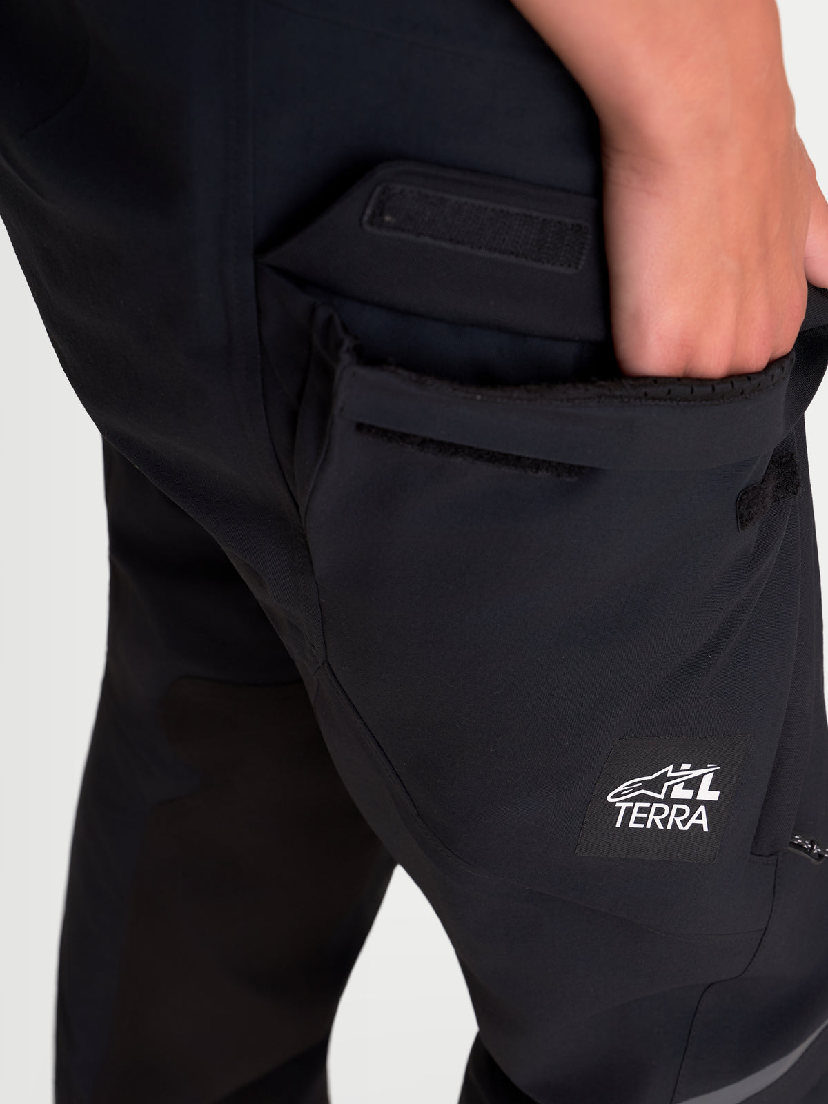 Alpinestars Stella ST-7 V2 2L Gore-Tex Spodnie turystyczne adventure damskie krótkie, czarne, zbliżenie pokazujące wodoodporną kieszeń cargo i detal z logo All Terra na modelu
