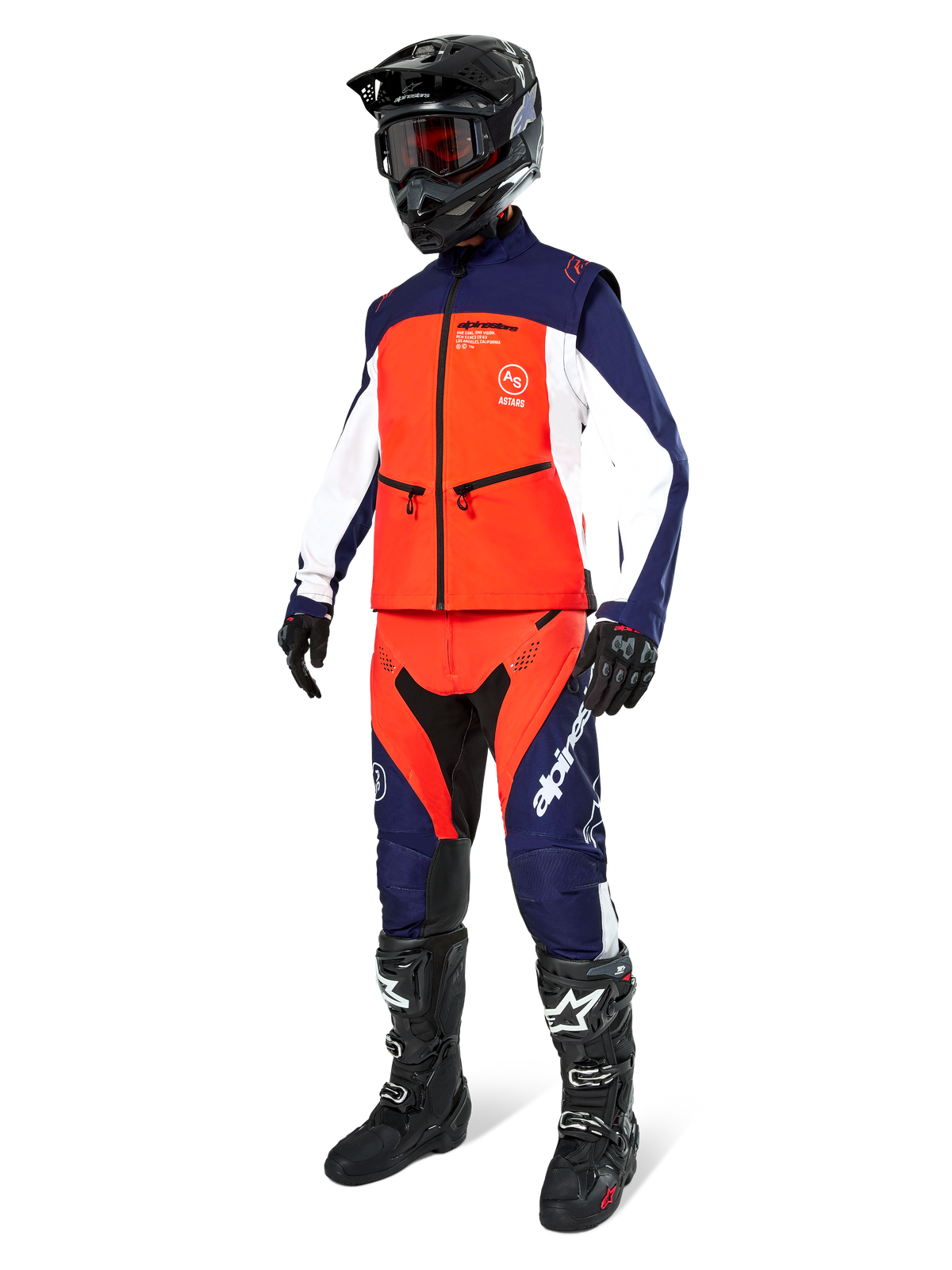 Motocyklista motocrossowy ubrany w kurtkę Alpinestars Lite-Dura Softshell w kolorach granatowym, jaskrawym pomarańczowym i białym, pasujące spodnie off-road, czarny kask z goglami i czarne buty wyścigowe, skoordynowany zestaw odzieży enduro