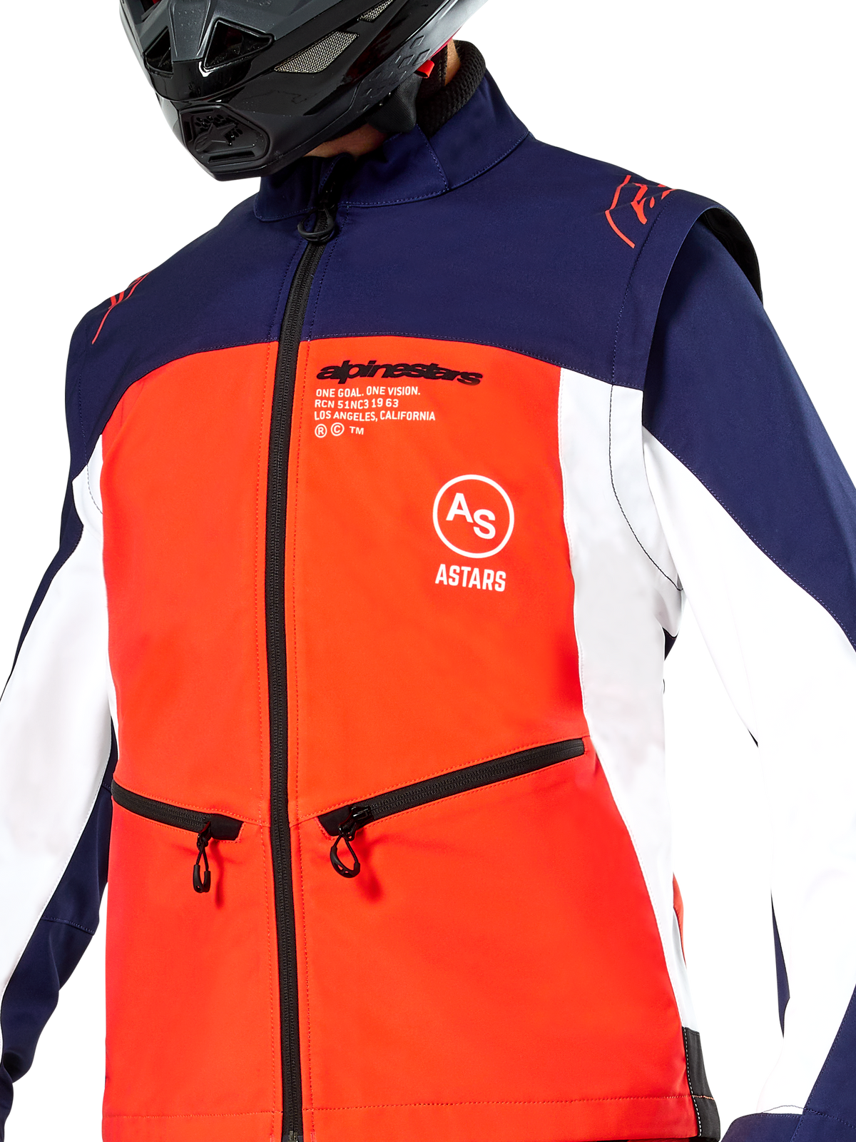 Kurtka Alpinestars Lite-Dura Softshell w kolorach granatowym, jaskrawopomarańczowym i białym, zbliżenie na tors, jaskrawopomarańczowy panel przedni, białe panele boczne i granatowe ramiona, kieszenie zapinane na zamek, wyraźne logo Alpinestars, motocyklista w czarnym kasku off-road