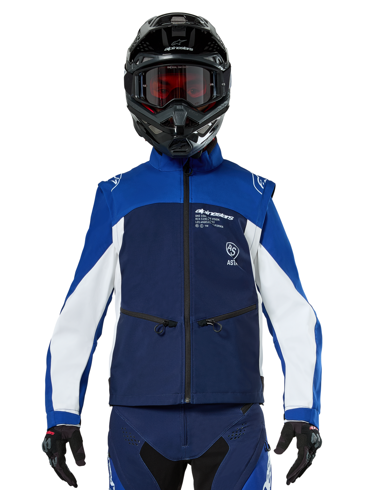 Motocross rider wearing the Alpinestars Lite-Dura Softshell Jacket in Navy Bright Blue White, front view, paired with a black helmet and red-tinted goggles, featuring a technical windproof design with zippered pockets and white accents for off-road enduro riding