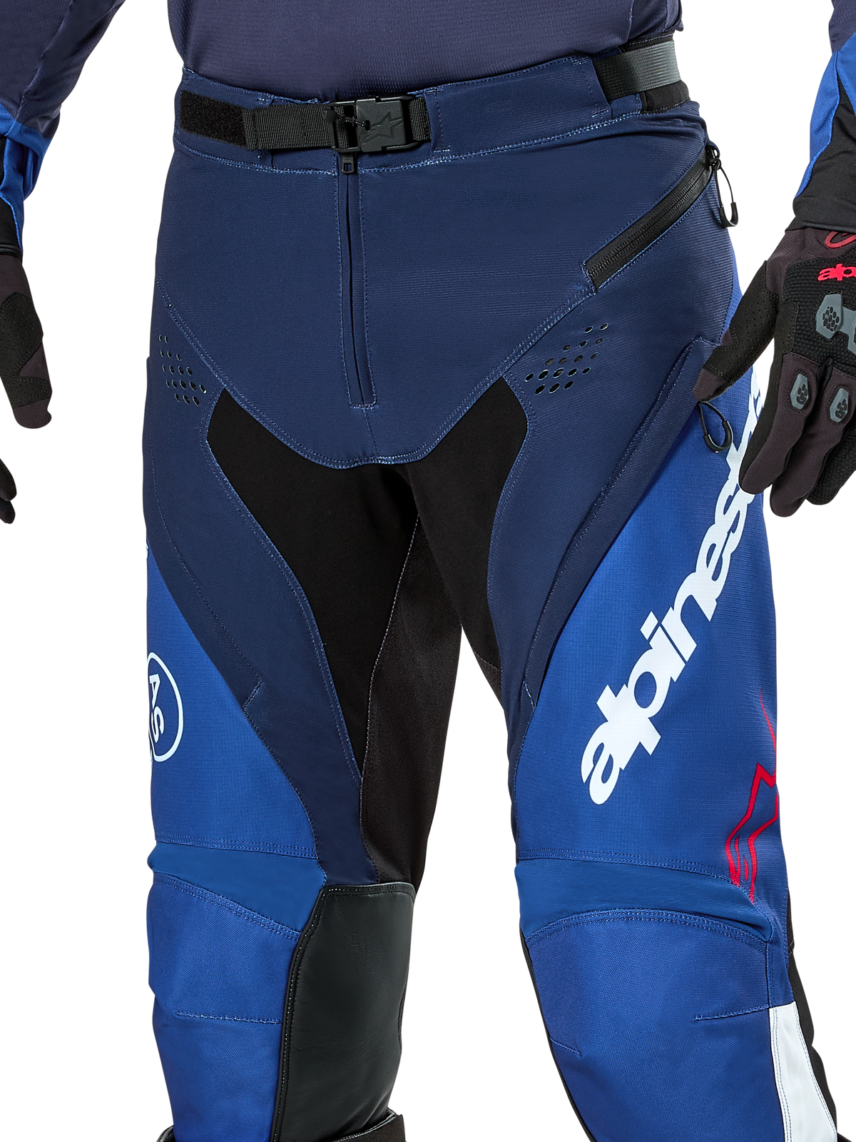Alpinestars Pro-Dura Pants, spodnie do enduro i motocrossu, granatowe, jasnoniebieskie i białe, widok z bliska na magnetyczne zapięcie SX2 w pasie, zapinane na zamek otwory wentylacyjne na udach oraz wytrzymałe, elastyczne panele z wyraźnym białym brandingiem.