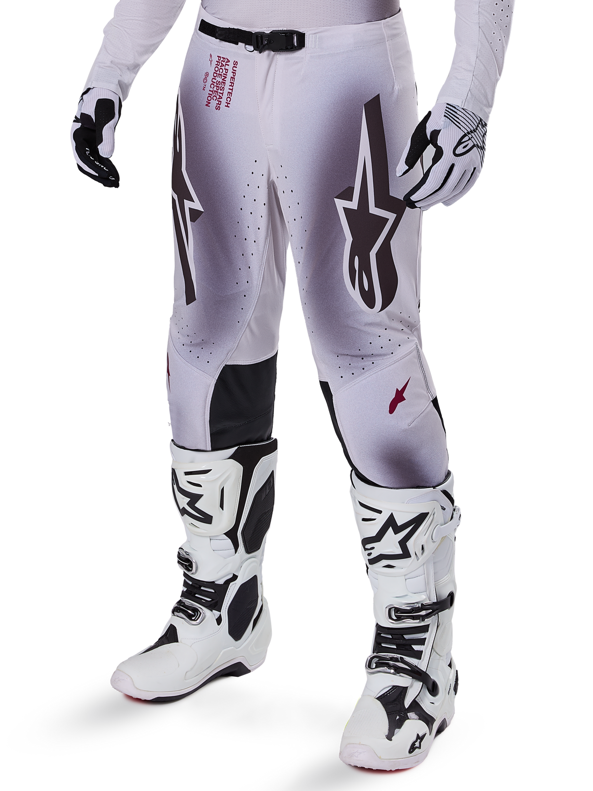 Alpinestars Supertech Maker Pants 2025, spodnie motocrossowe, srebrno-czarne, z dużym logo gwiazdy i czerwonymi napisami, prezentowane z dopasowanymi białymi butami i rękawicami
