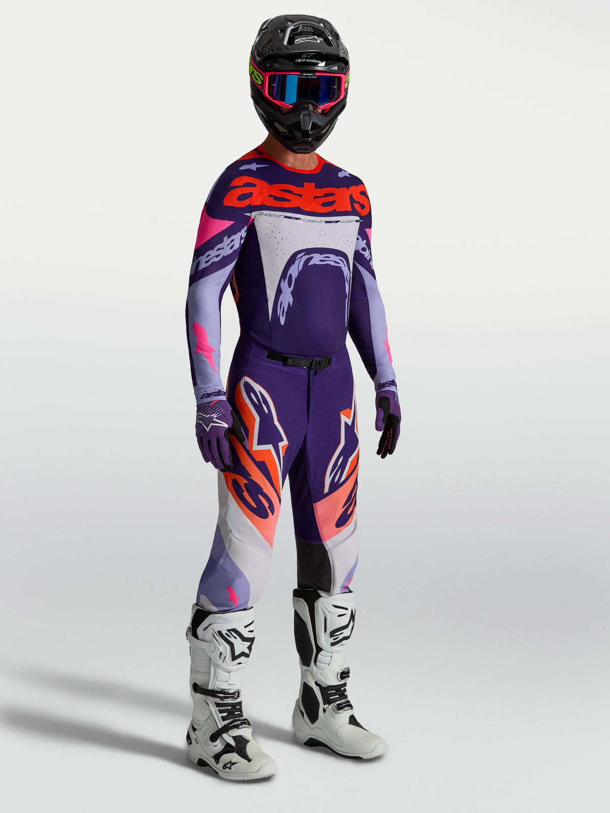 Alpinestars Supertech Dyna, męskie spodnie motocrossowe, fioletowe i różowe fluo, komplet z koszulką i białymi butami.